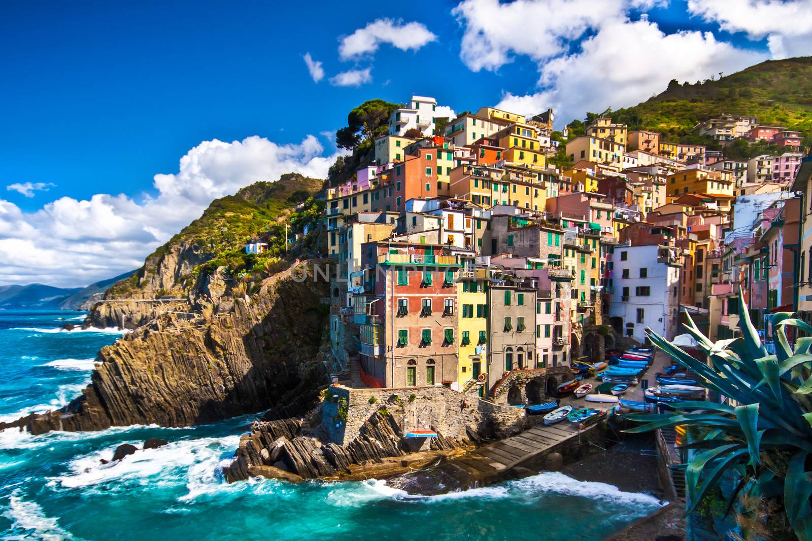 Riomaggiore fisherman village in a dramatic windy weather. Riomaggiore is one of five famous colorful villages of Cinque Terre in Italy, suspended between sea and land on sheer cliffs upon the  turquoise sea.