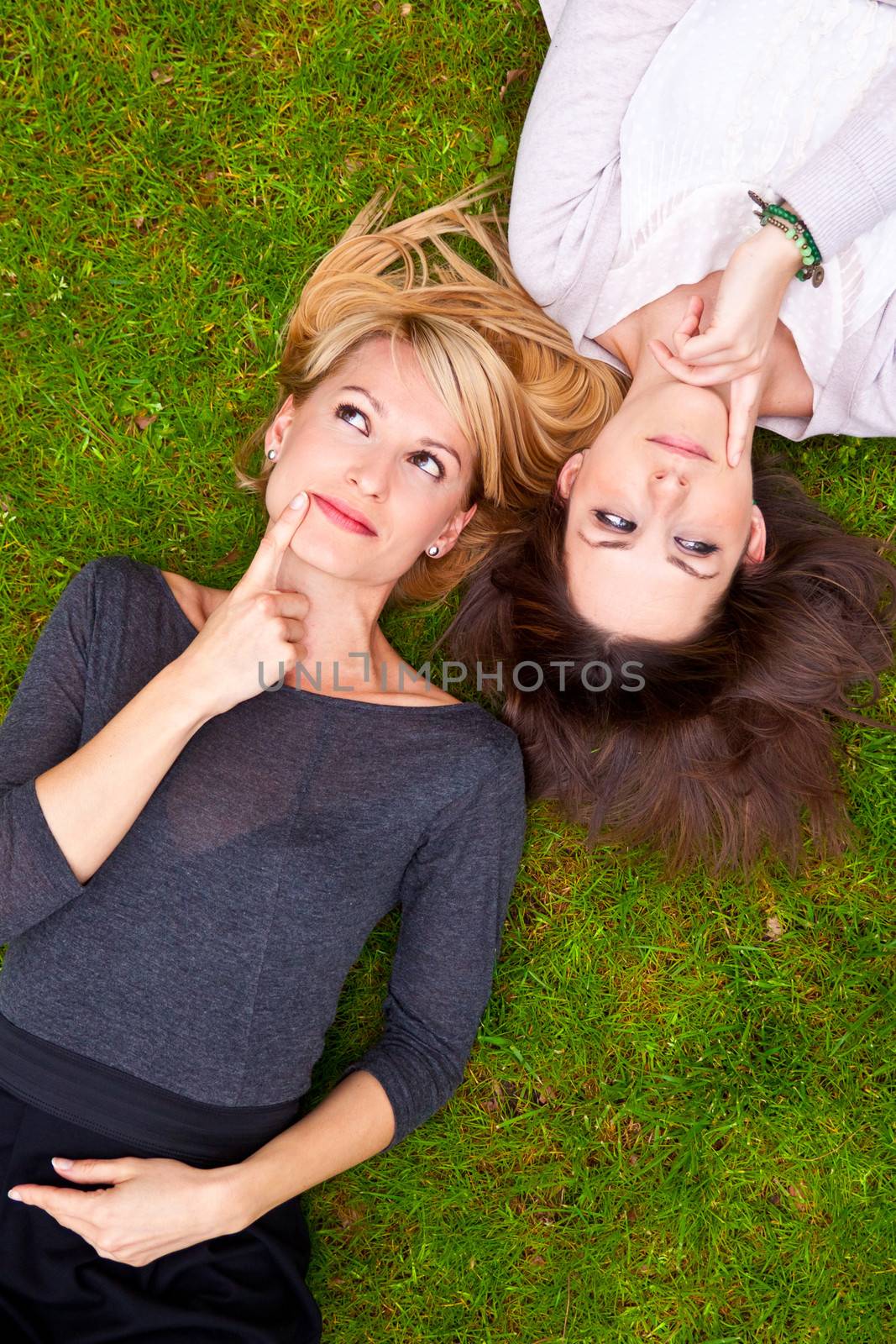 Two thoughtful girls lying in the grass by kasto