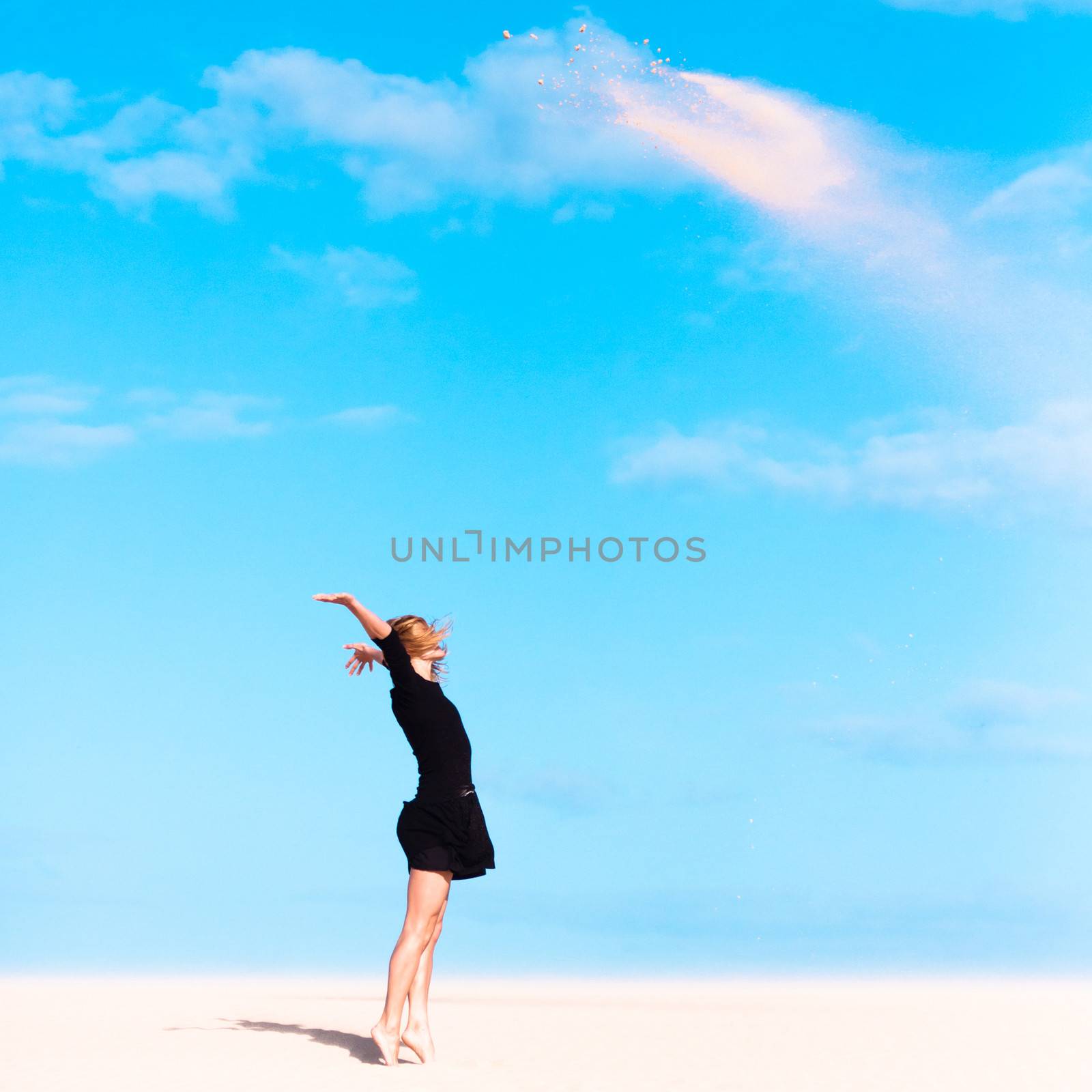 Beautifull girl playing with the sand on the dune.