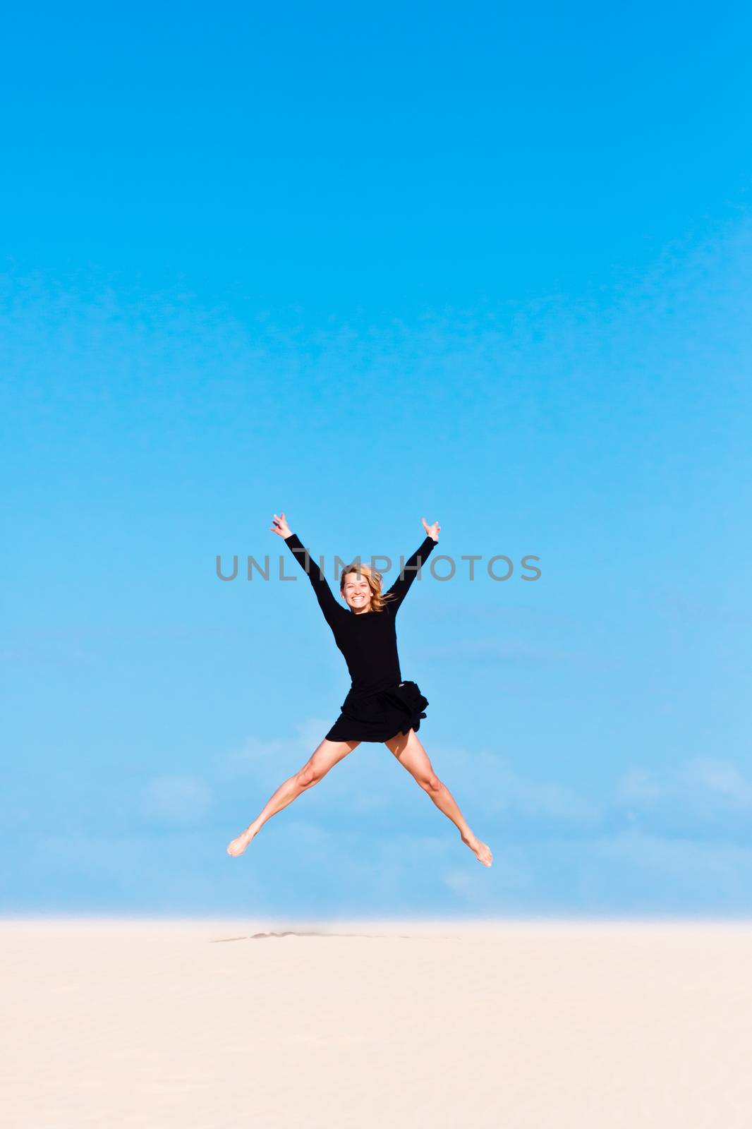 Beautifull girl jumping on the sand  dune.