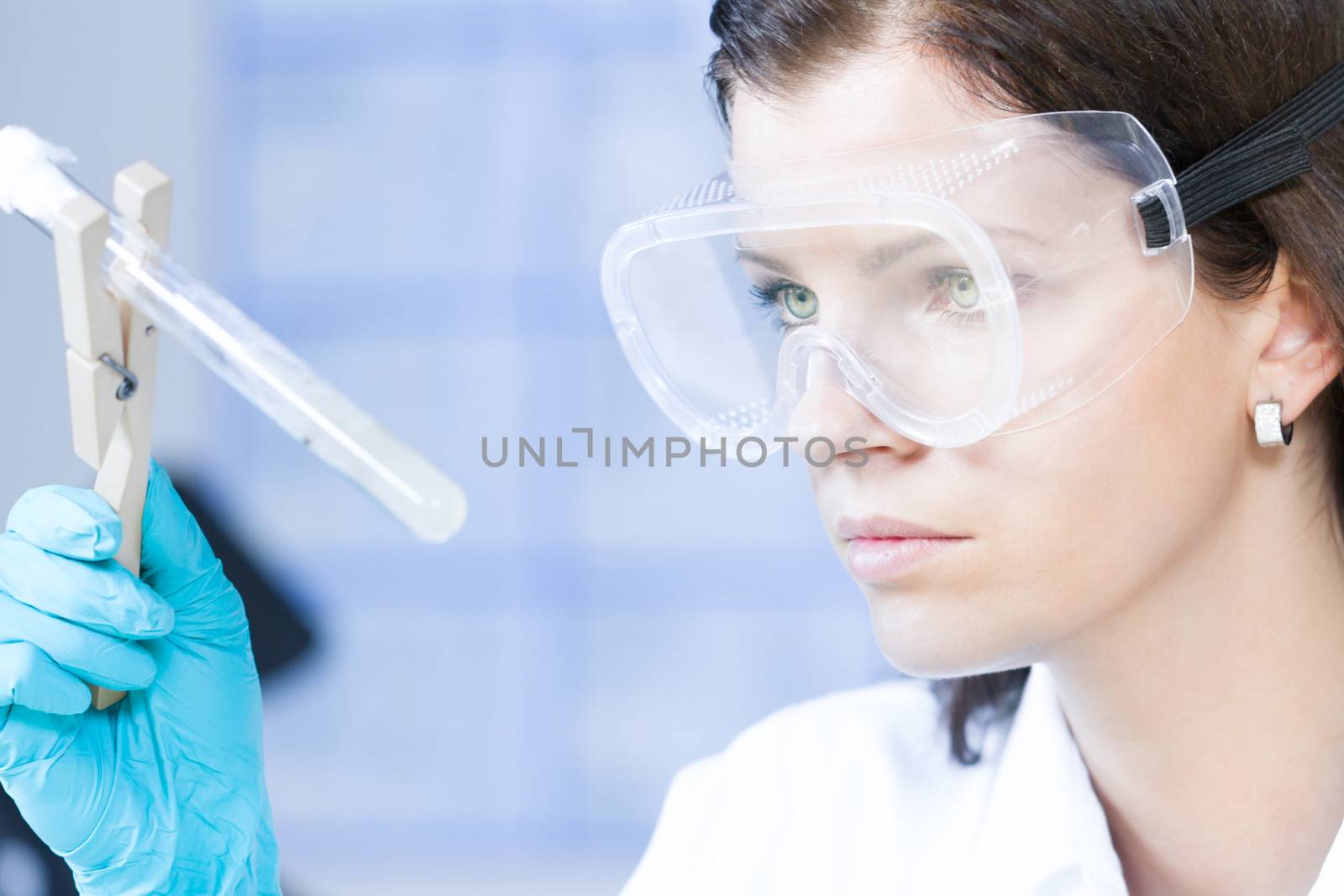 Attractive young female scientist observing bacterial colonies in the glass tube in the life science research laboratory (biochemistry, genetics, forensics, microbiology..)