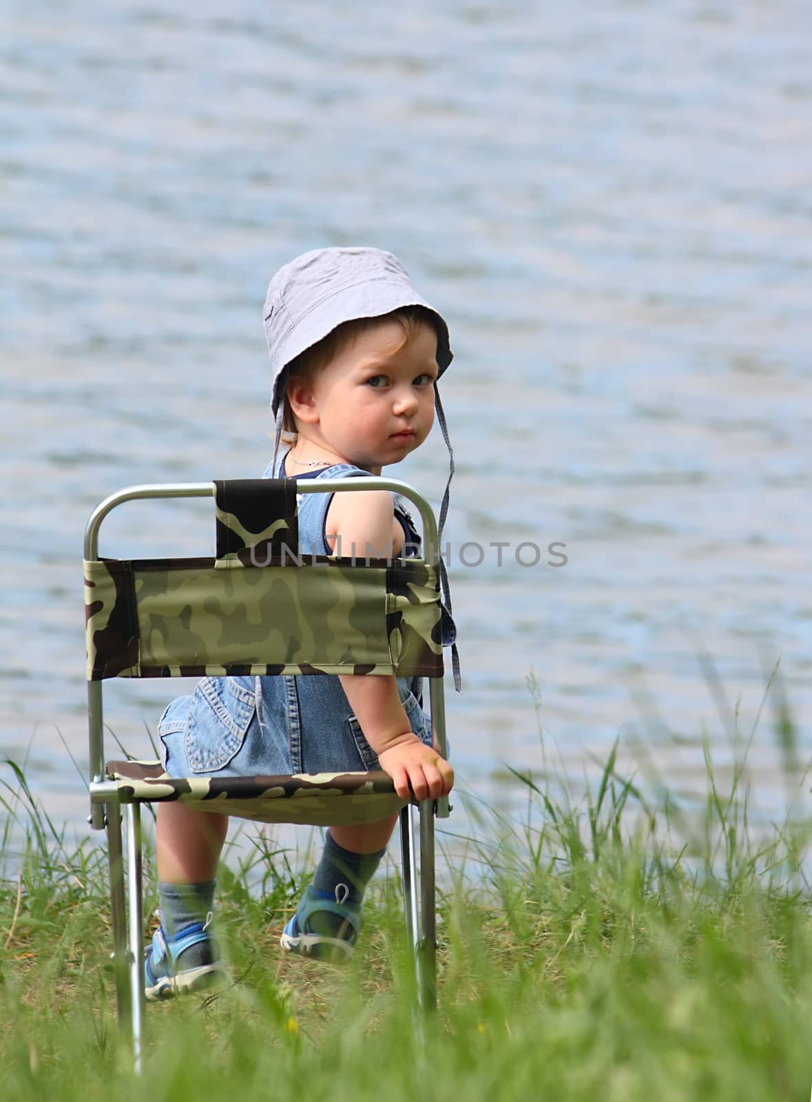 Little boy sitting near the lake