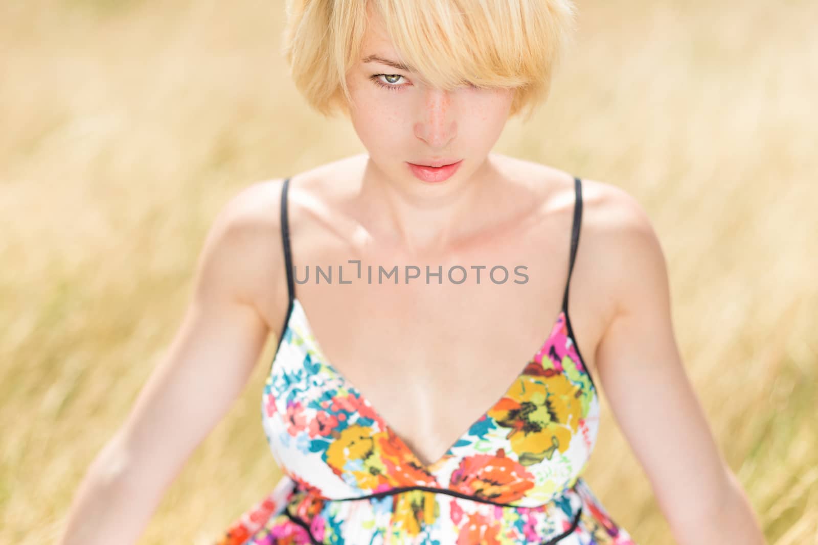 A portrait of a casual dressed beautiful young Caucasian woman outdoor in the meadow on a sunny summer day.