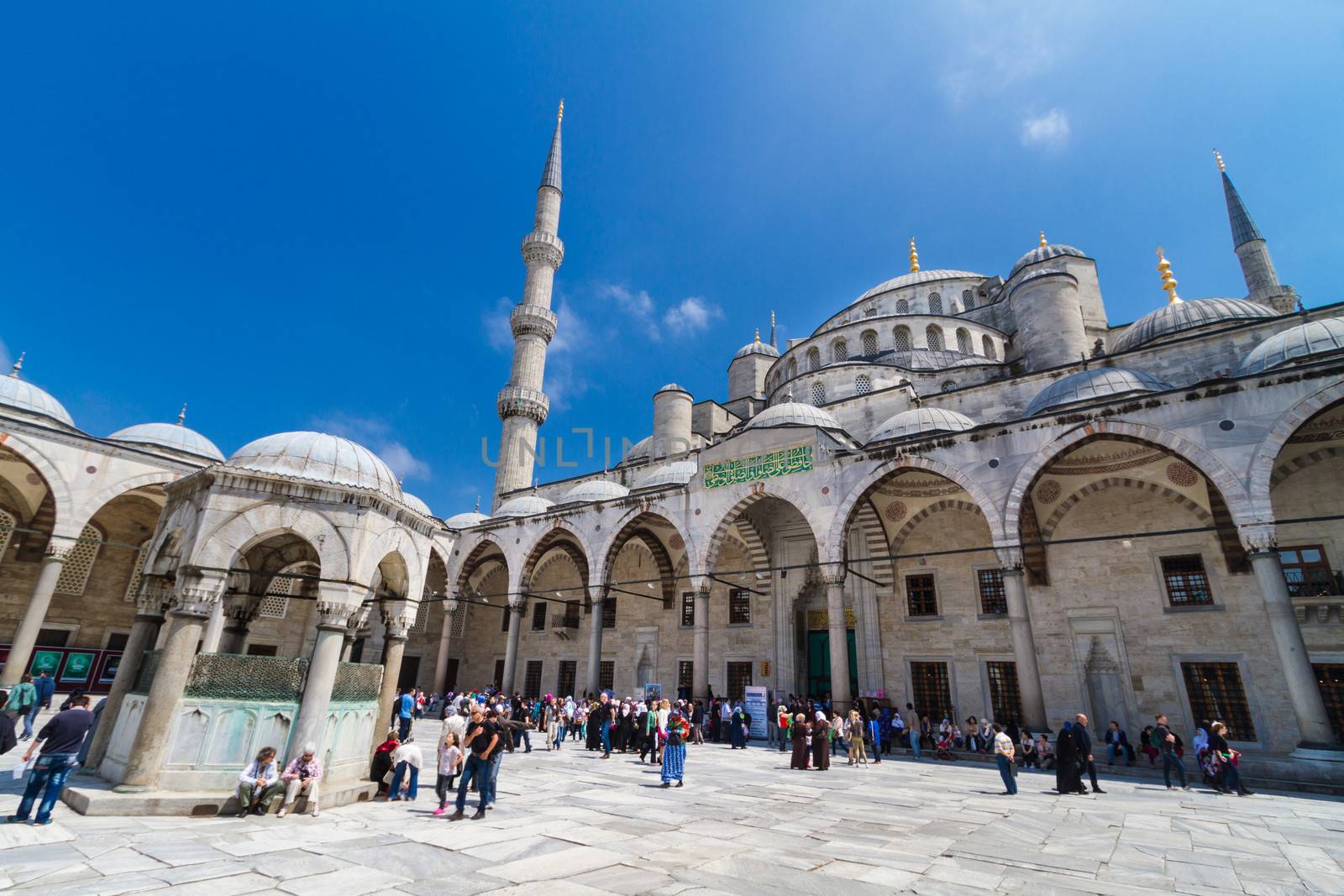 ISTANBUL - MAY 7: Tourists and prayers mixing at courtyard of Blue mosque on May 7, 2013 in Istanbul, Turkey; While still used as a mosque, the Sultan Ahmed Mosque has also become a popular tourist attraction.