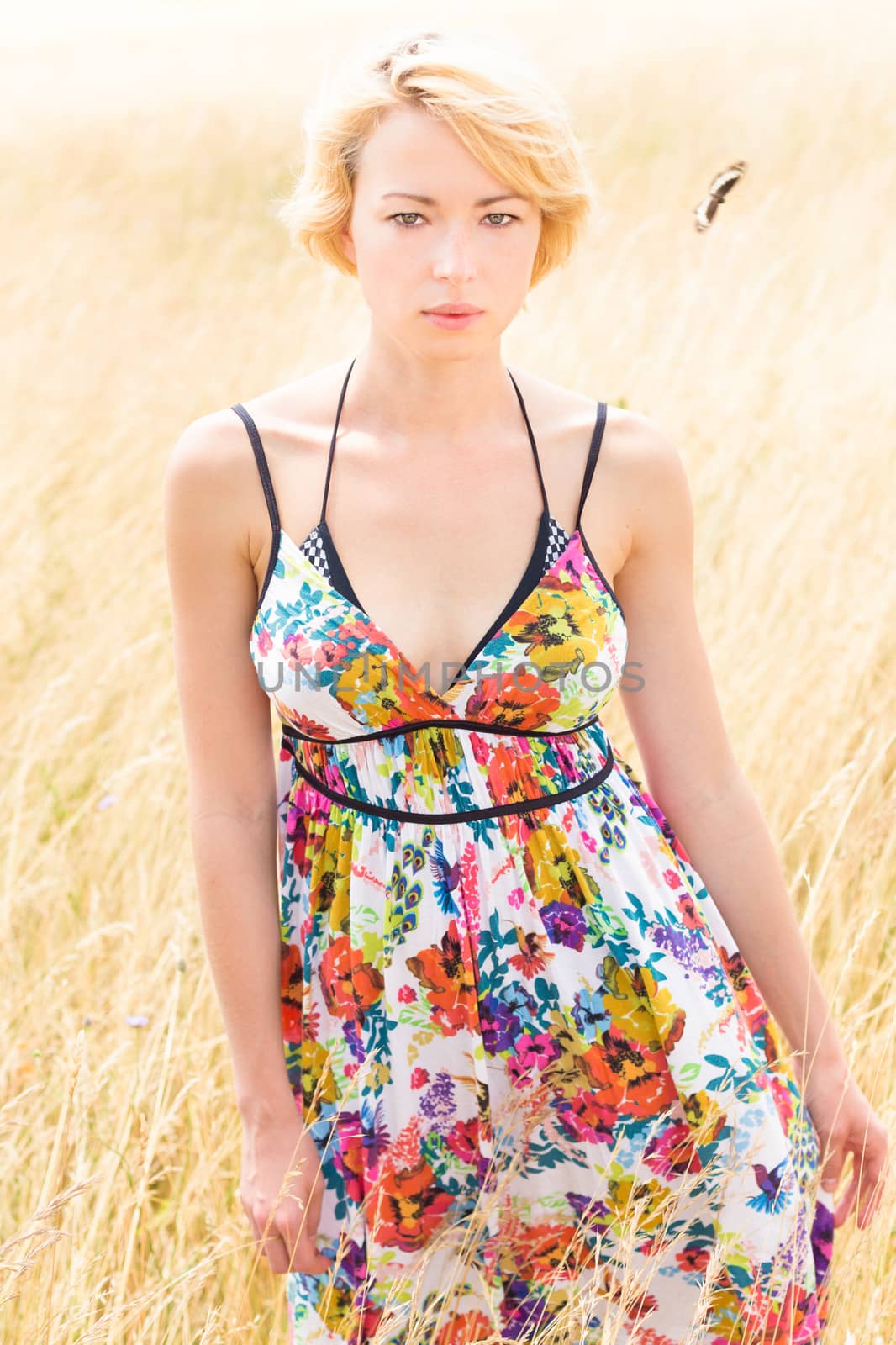 A portrait of a casual dressed beautiful young Caucasian woman outdoor in the meadow on a sunny summer day.