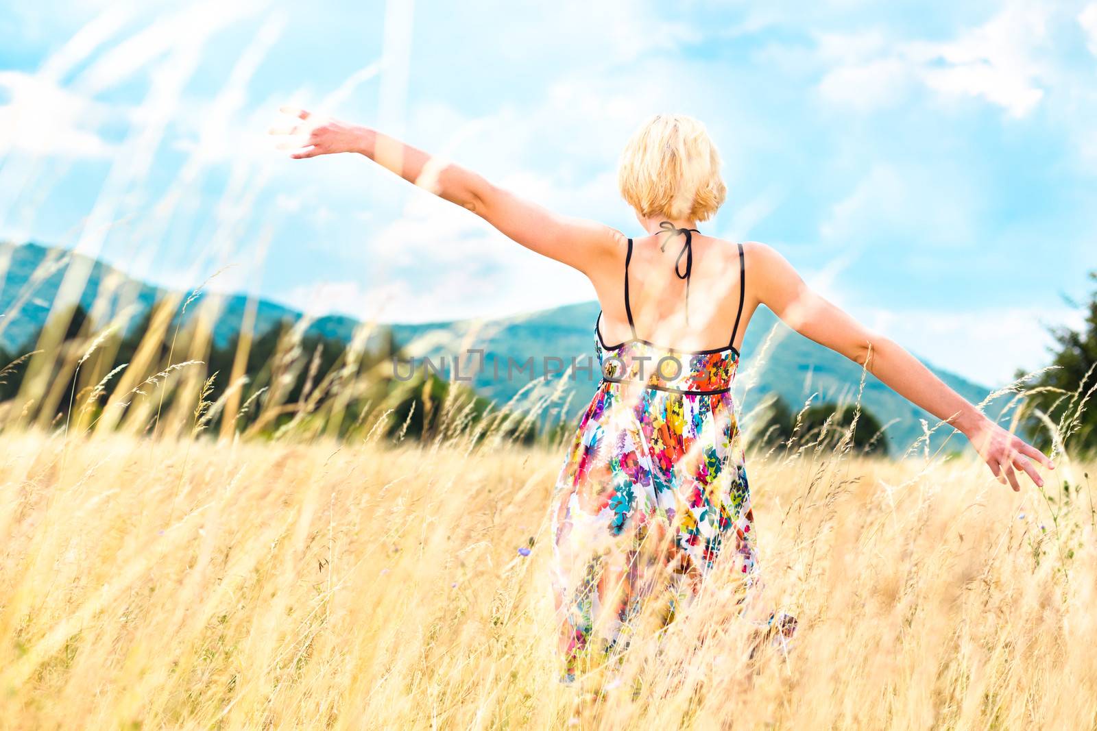 Lady enjoying the nature. Young woman arms raised enjoying the fresh air in summer meadow.