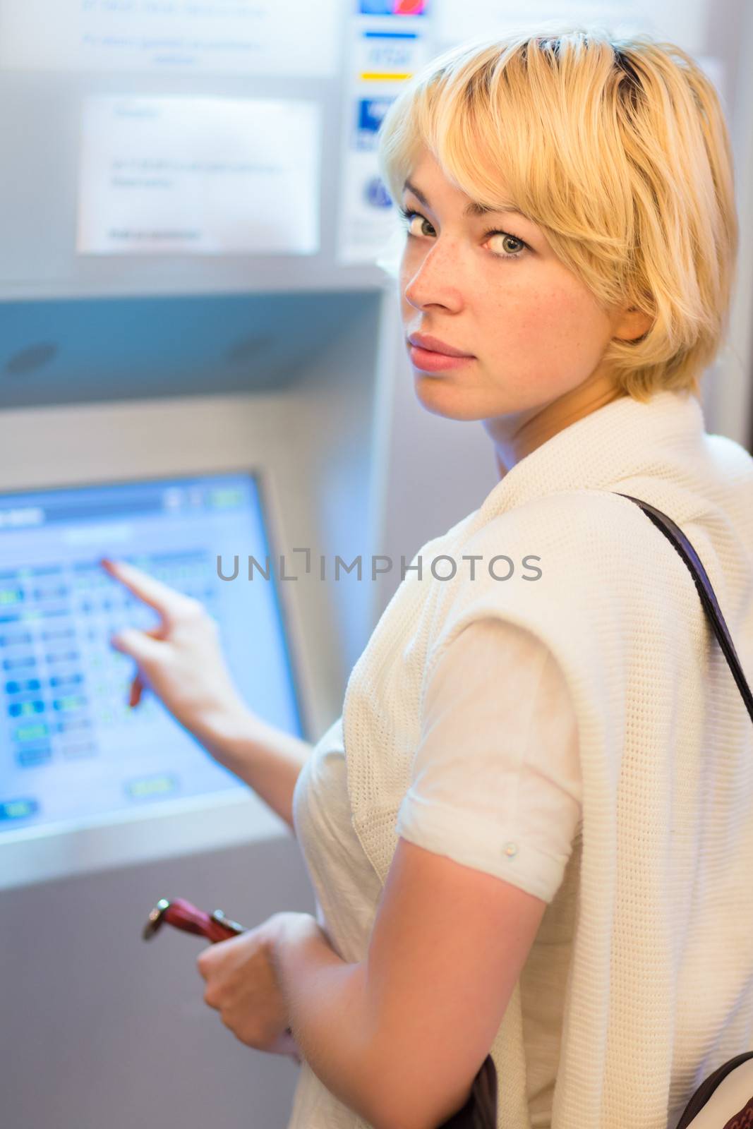 Lady buying a railway ticket at the automatic ticket vending machine with touch screen.