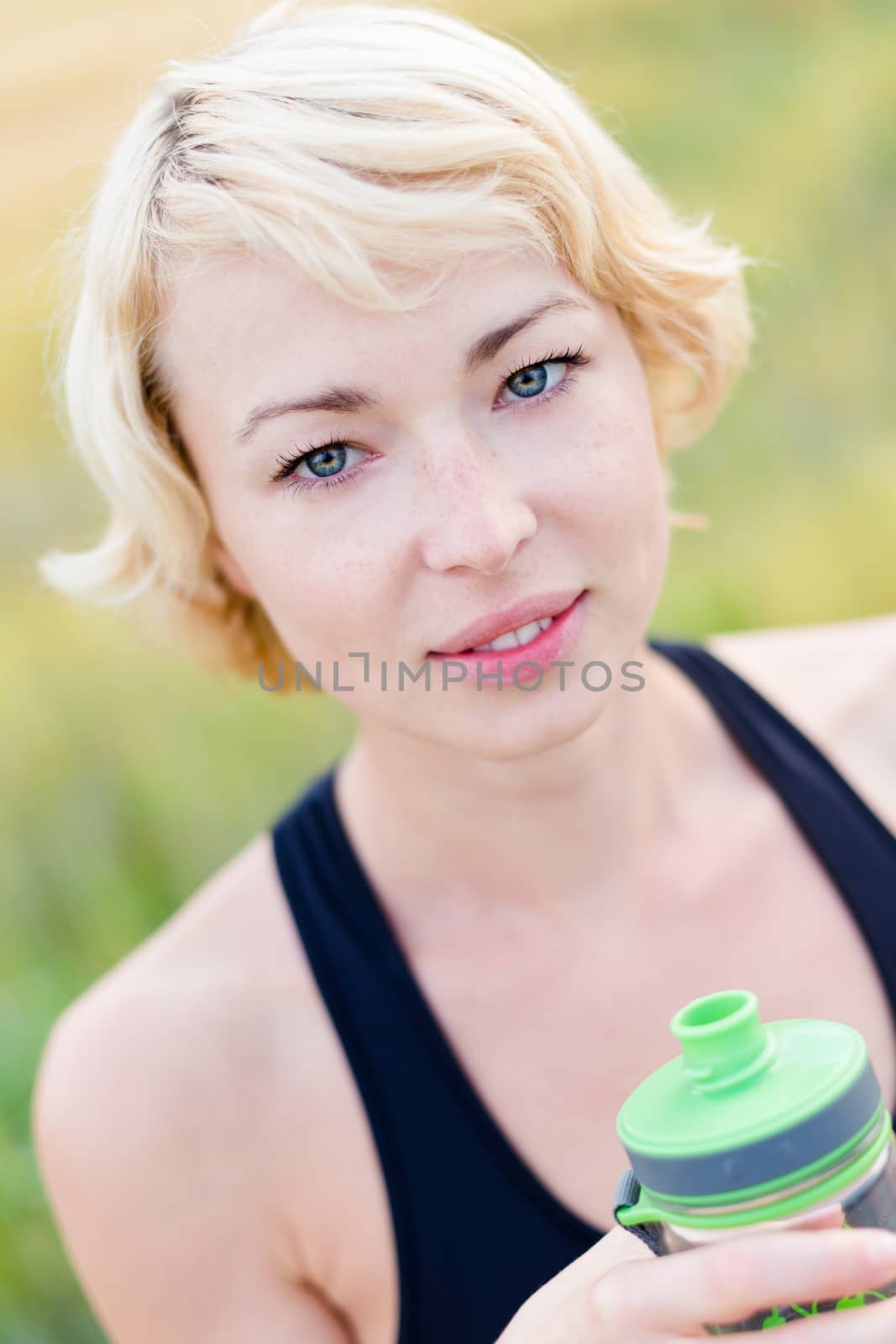 Lady holding a water bottle, hydrating during outdoor activities.