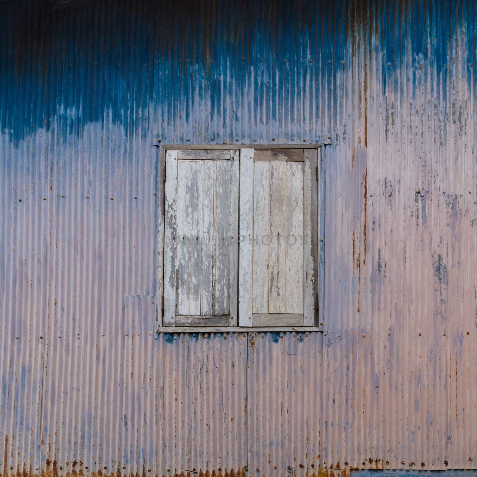 Old rusty house with closed wooden shutters; can be used as a graphical background.