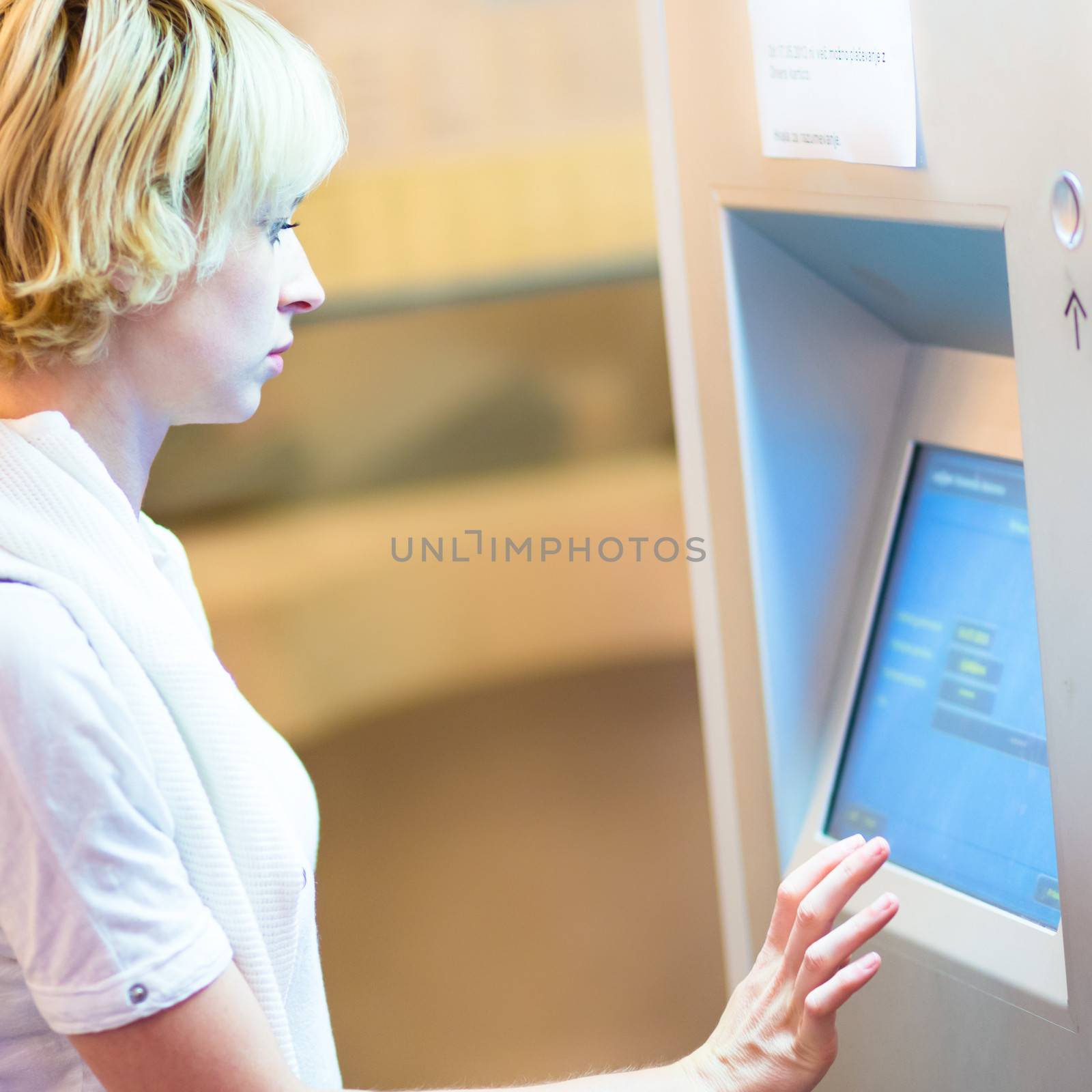 Lady buying a railway ticket at the automatic ticket vending machine with touch screen.