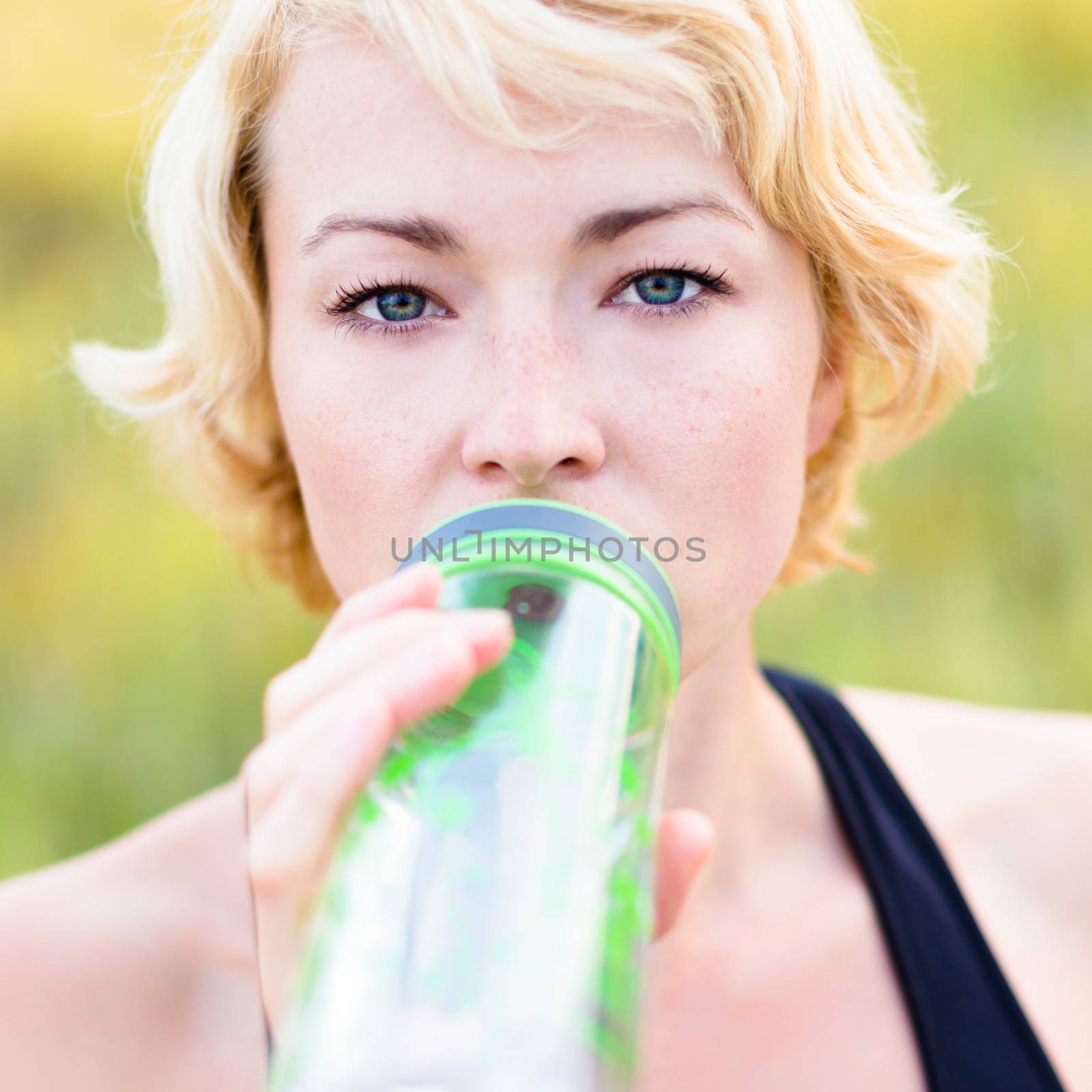 Lady drinking from the bottle during outdoor activities.