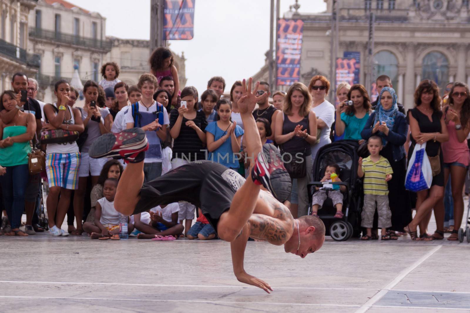 Street performer breakdancing in front of the random crowd. by kasto