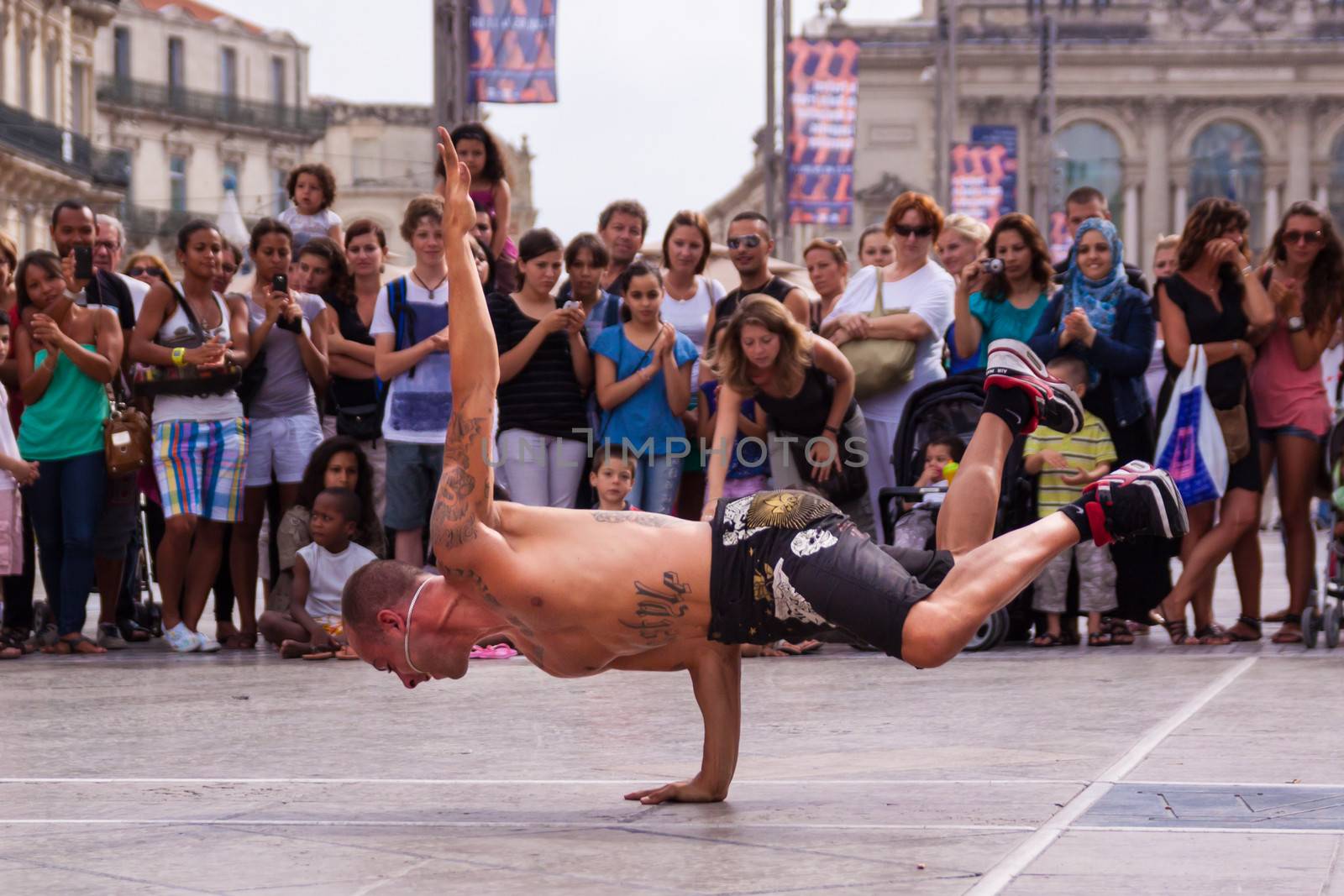 MONTPELLIER - JULY 12: Street performer breakdancing in front of the random crowd on July 12, 2011 in  Montpellier, France; B-boying or breaking is a style of street dance that originated among African American and Puerto Rican youths in New York City during the early 1970s.