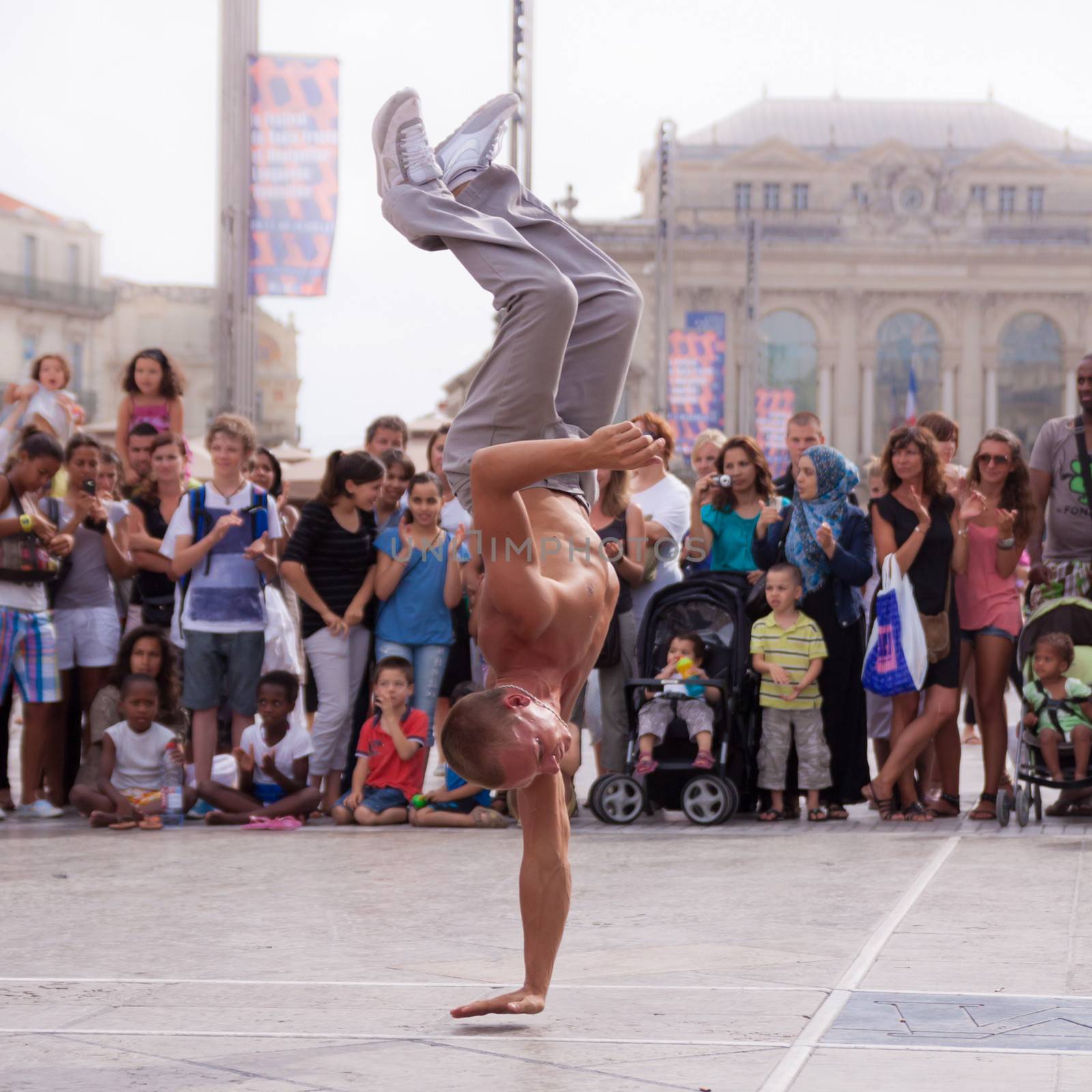 MONTPELLIER - JULY 12: Street performer breakdancing in front of the random crowd on July 12, 2011 in  Montpellier, France; B-boying or breaking is a style of street dance that originated among African American and Puerto Rican youths in New York City during the early 1970s.