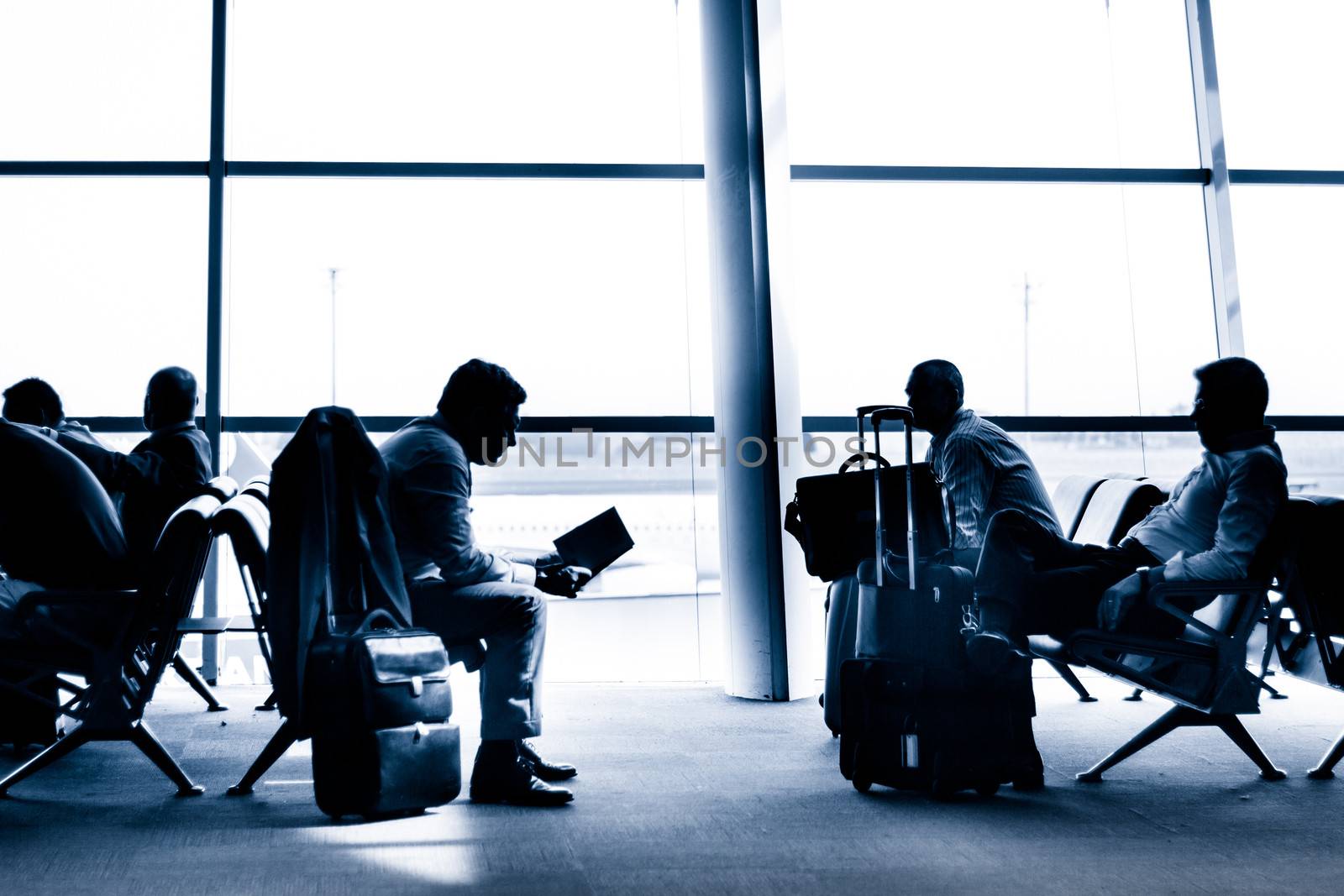 Silhouettes of business people traveling on airport; waiting at the plane boarding gates.