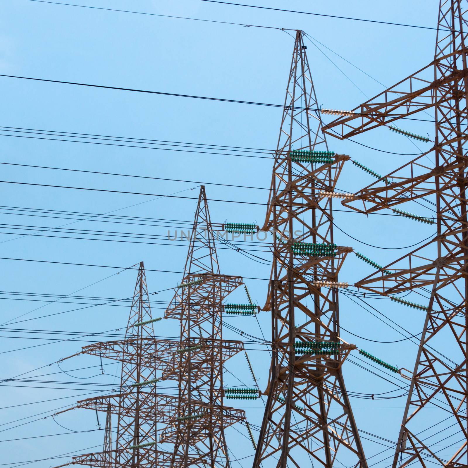 High-voltage power transmission towers in clear blue sky background.