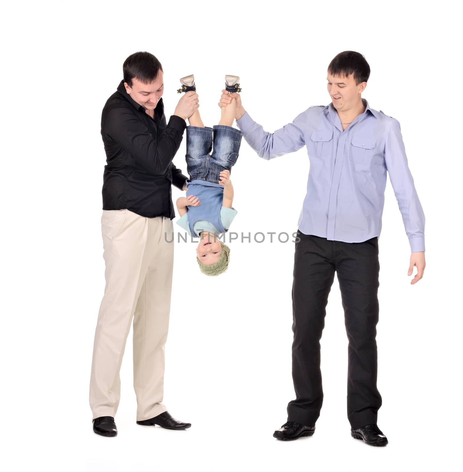 Two gusd holding little boy upside down at the white background