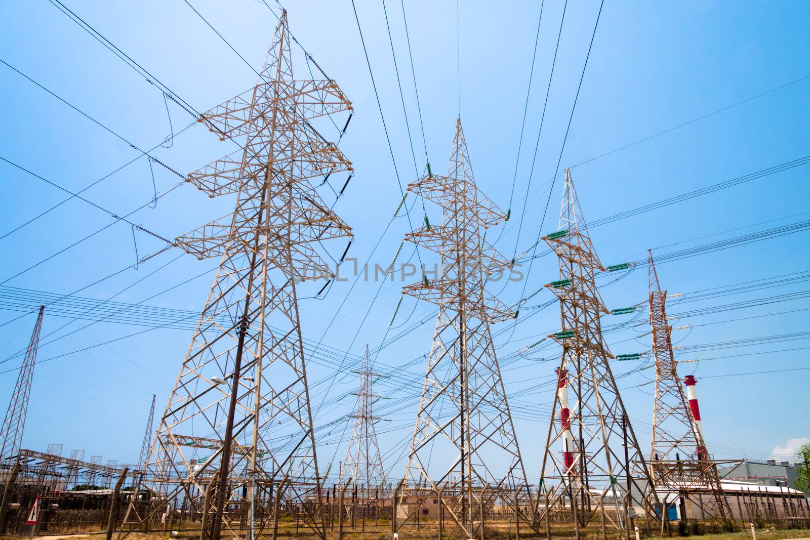 High-voltage power transmission towers in clear blue sky background.