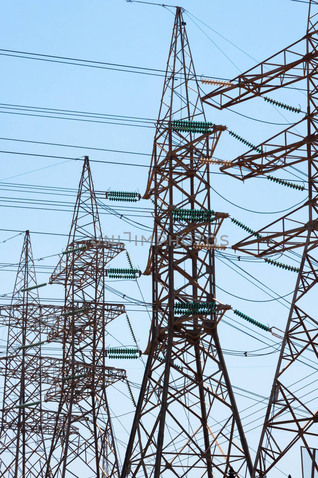 High-voltage power transmission towers in clear blue sky background.