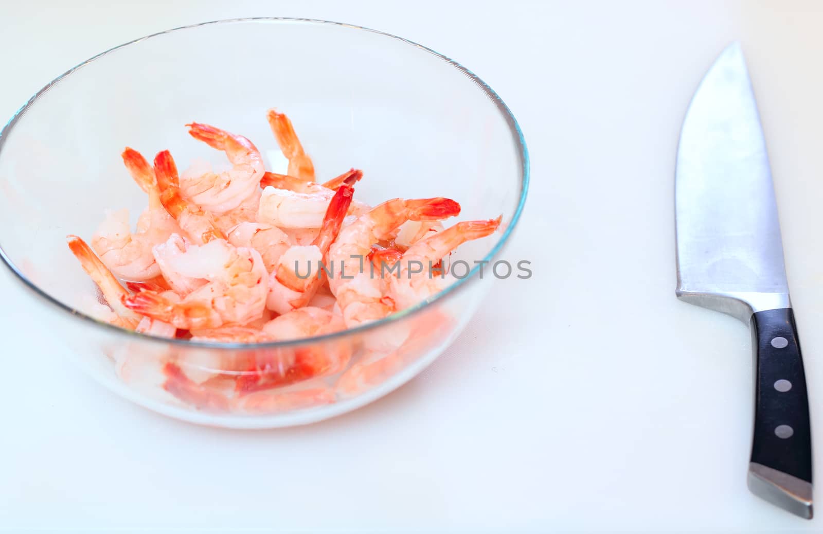 A lot of prepared tiger shrimps and knife at the desk