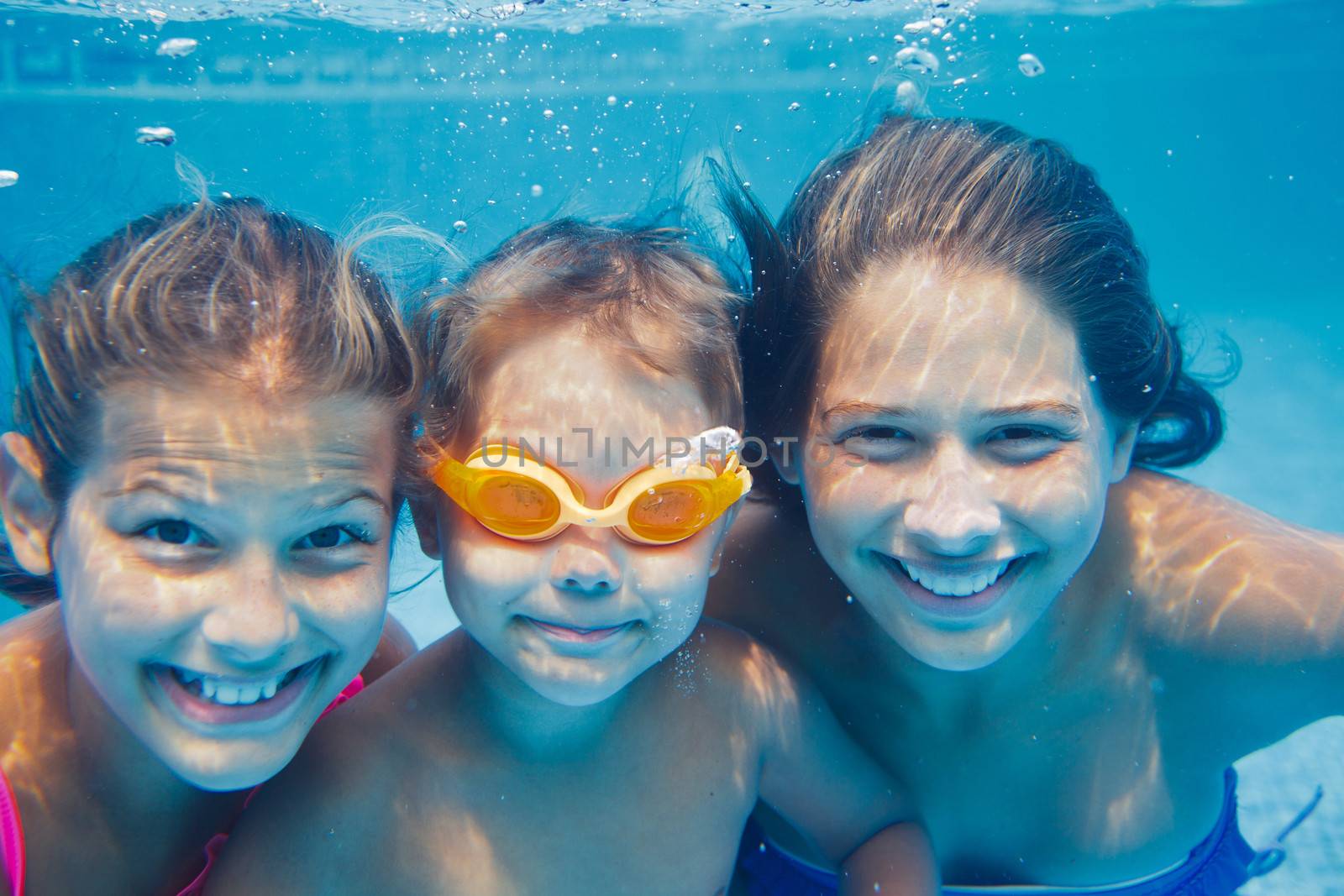 Close-up underwater portrait of the three cute smiling kids