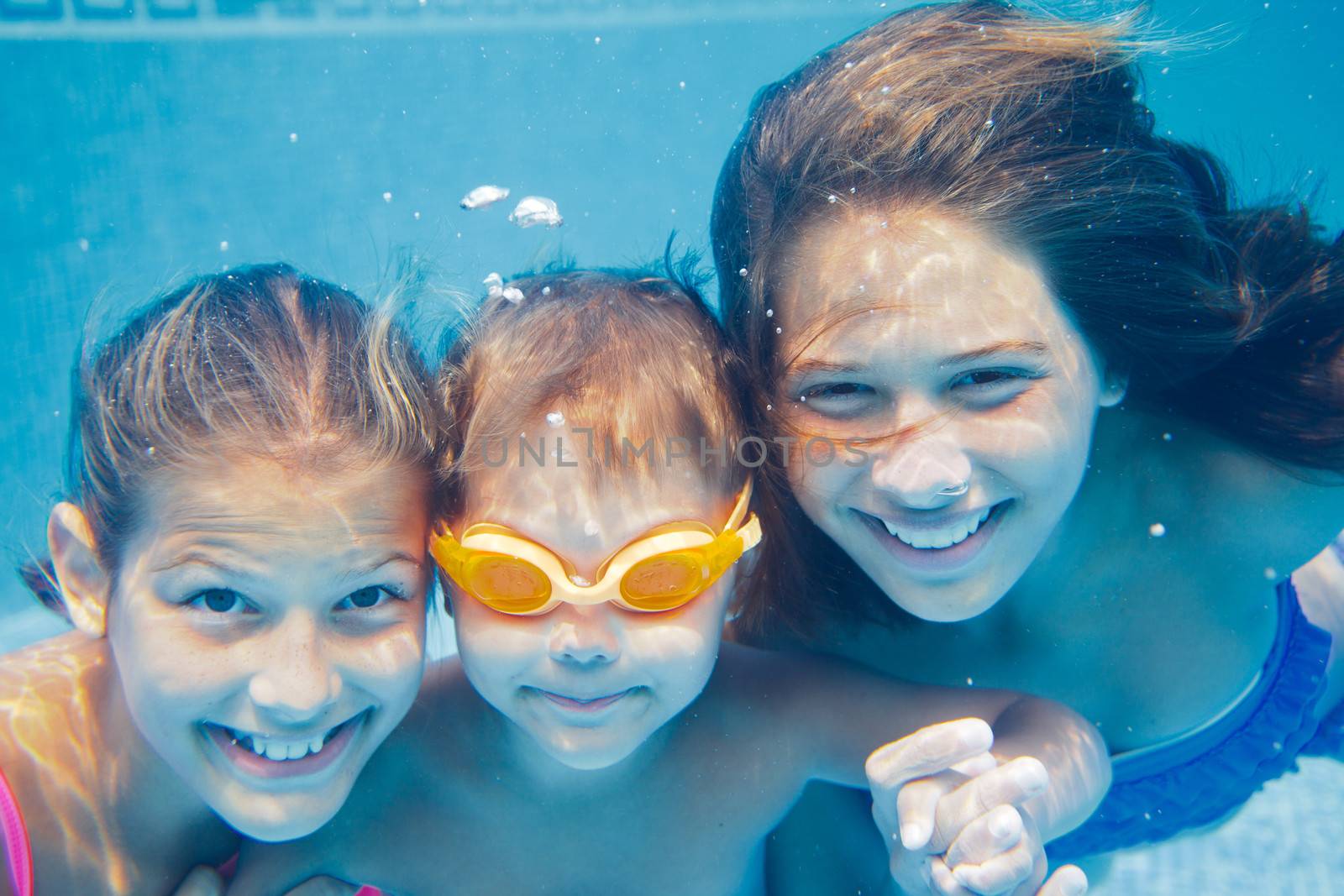 Close-up underwater portrait of the three cute smiling kids