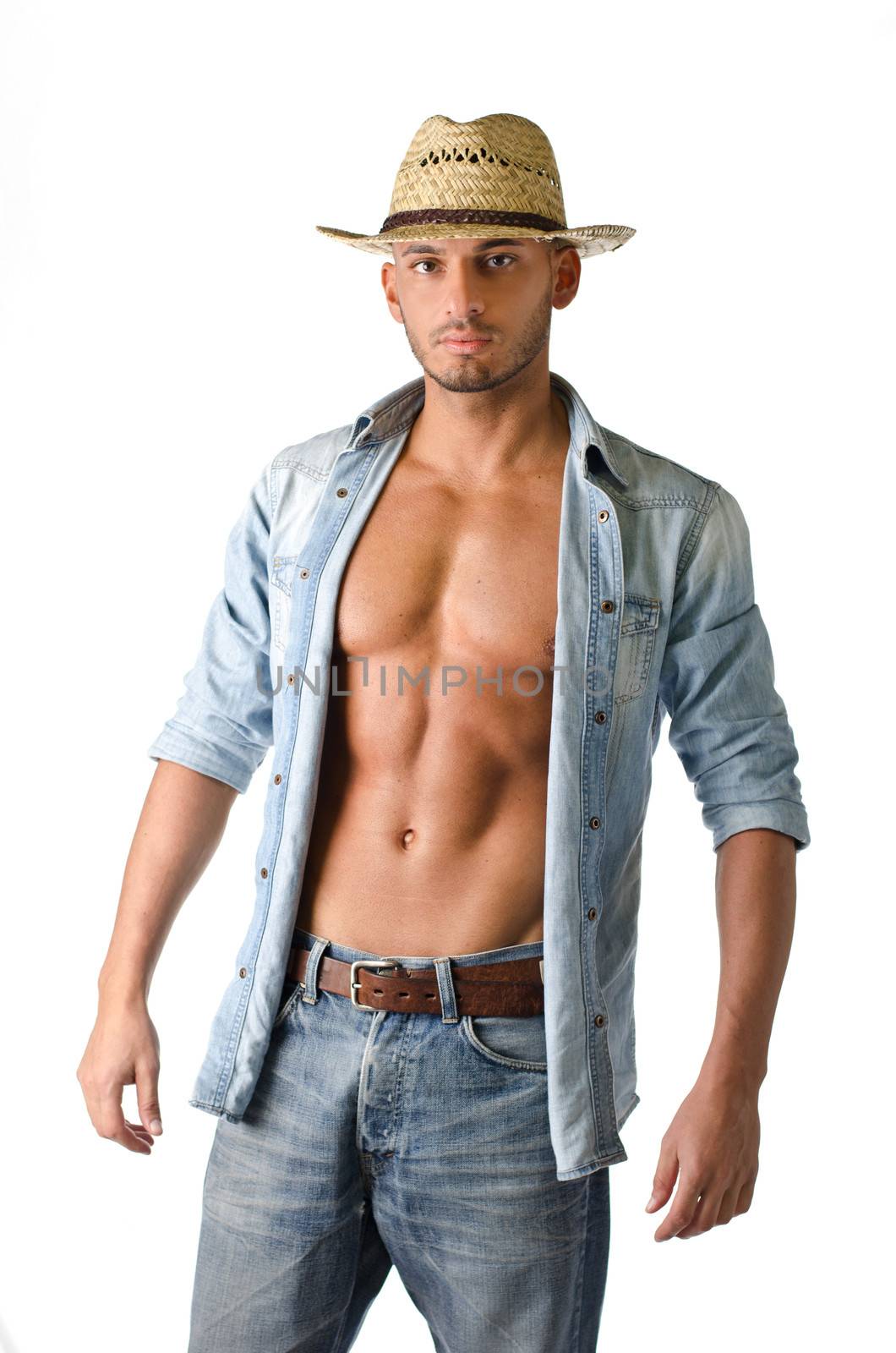 Trendy young man with jeans, open denim shirt and straw hat, looking at camera