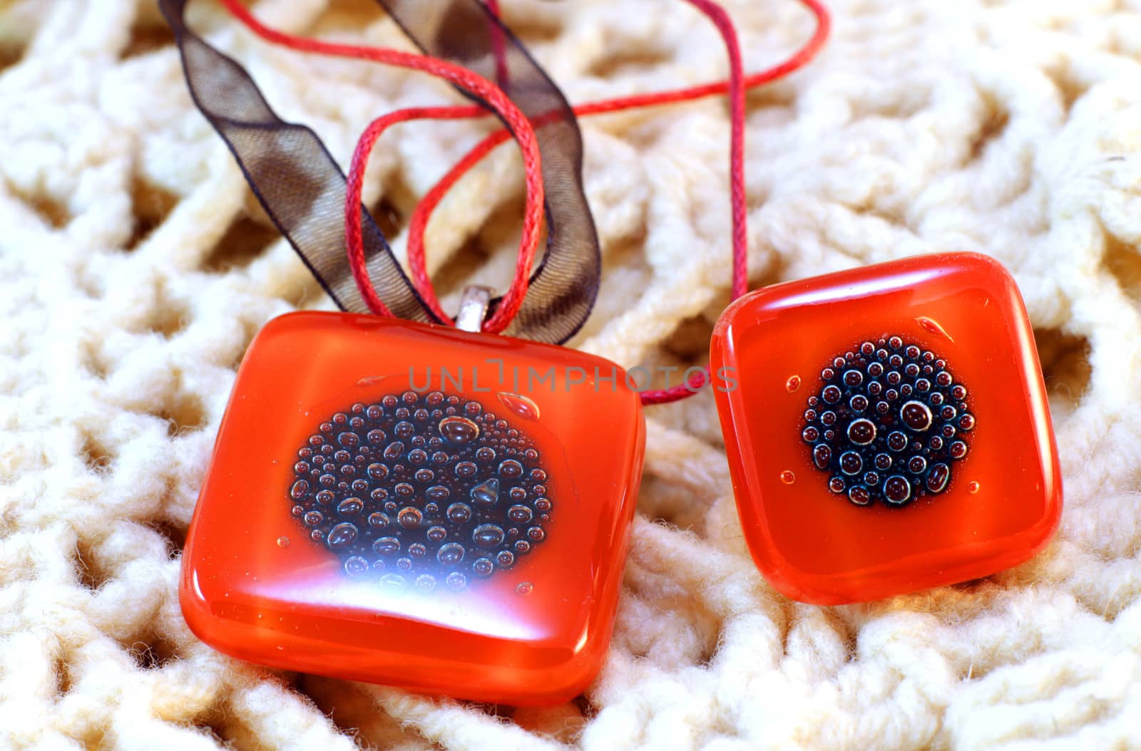 origina red glass handmade ring and amulet on knitted background 