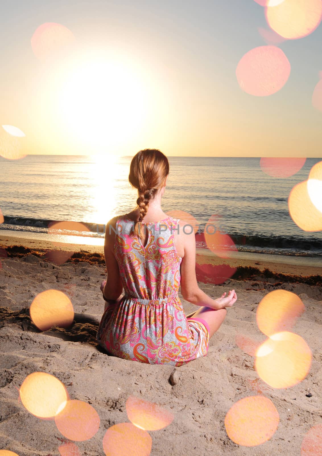woman meditating on beach with sun flares