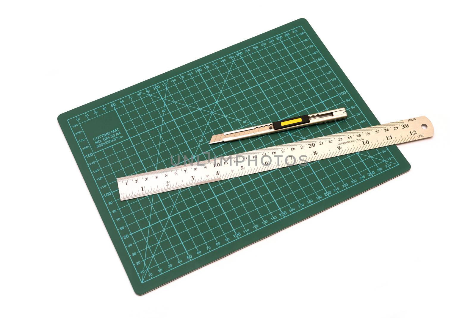 Green cutting mats with iron ruler and cuter isolated on white background