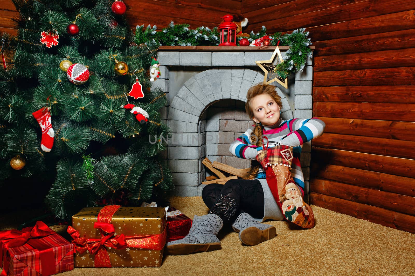 Cute little girl sitting at Christmas tree and gifts examines