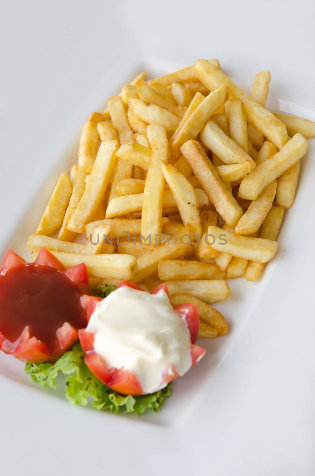 a pile of appetizing french fries on white plate with tomato sauce and cream sauce