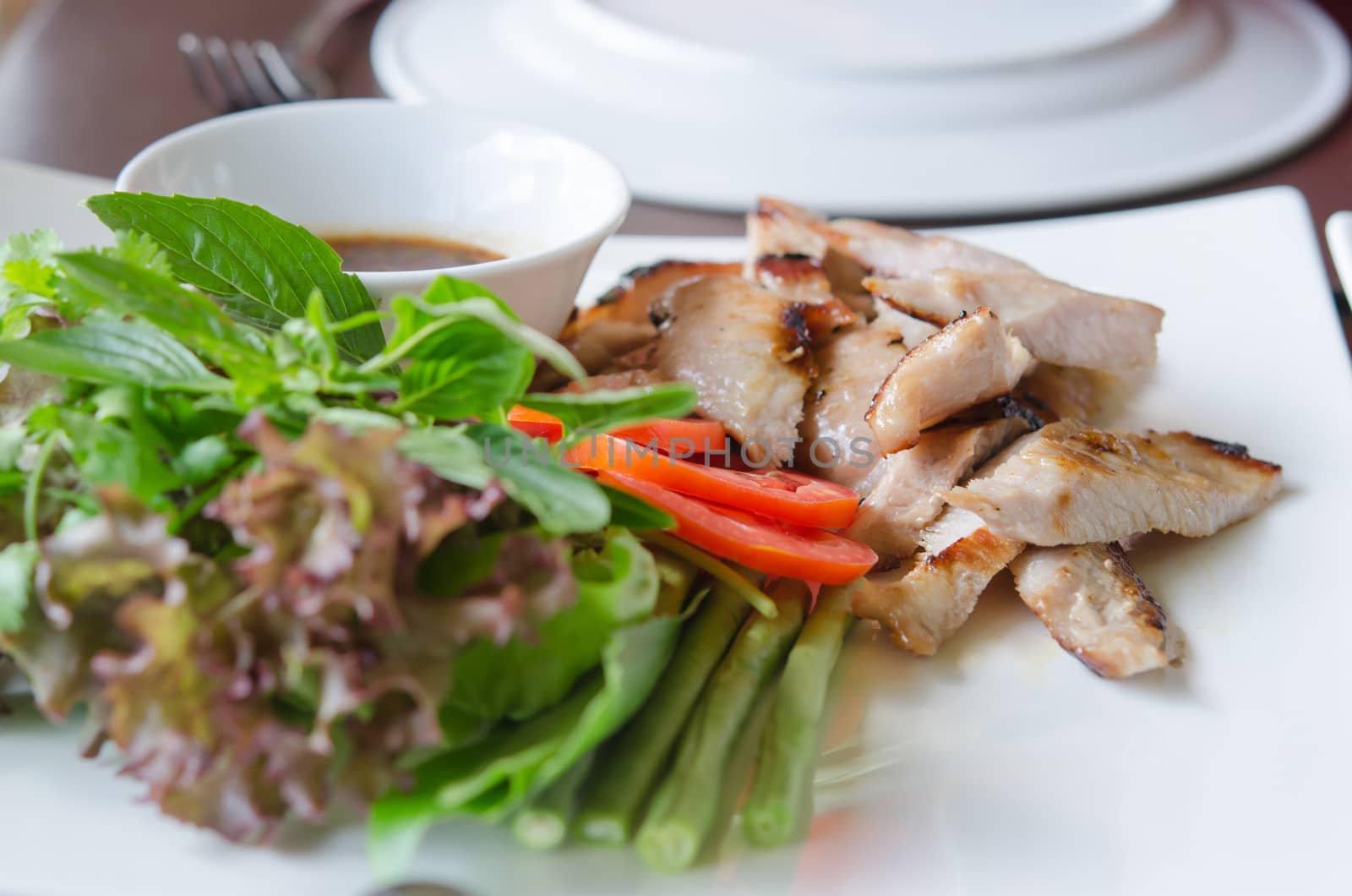 slice grilled pork  served with fresh vegetable on white dish