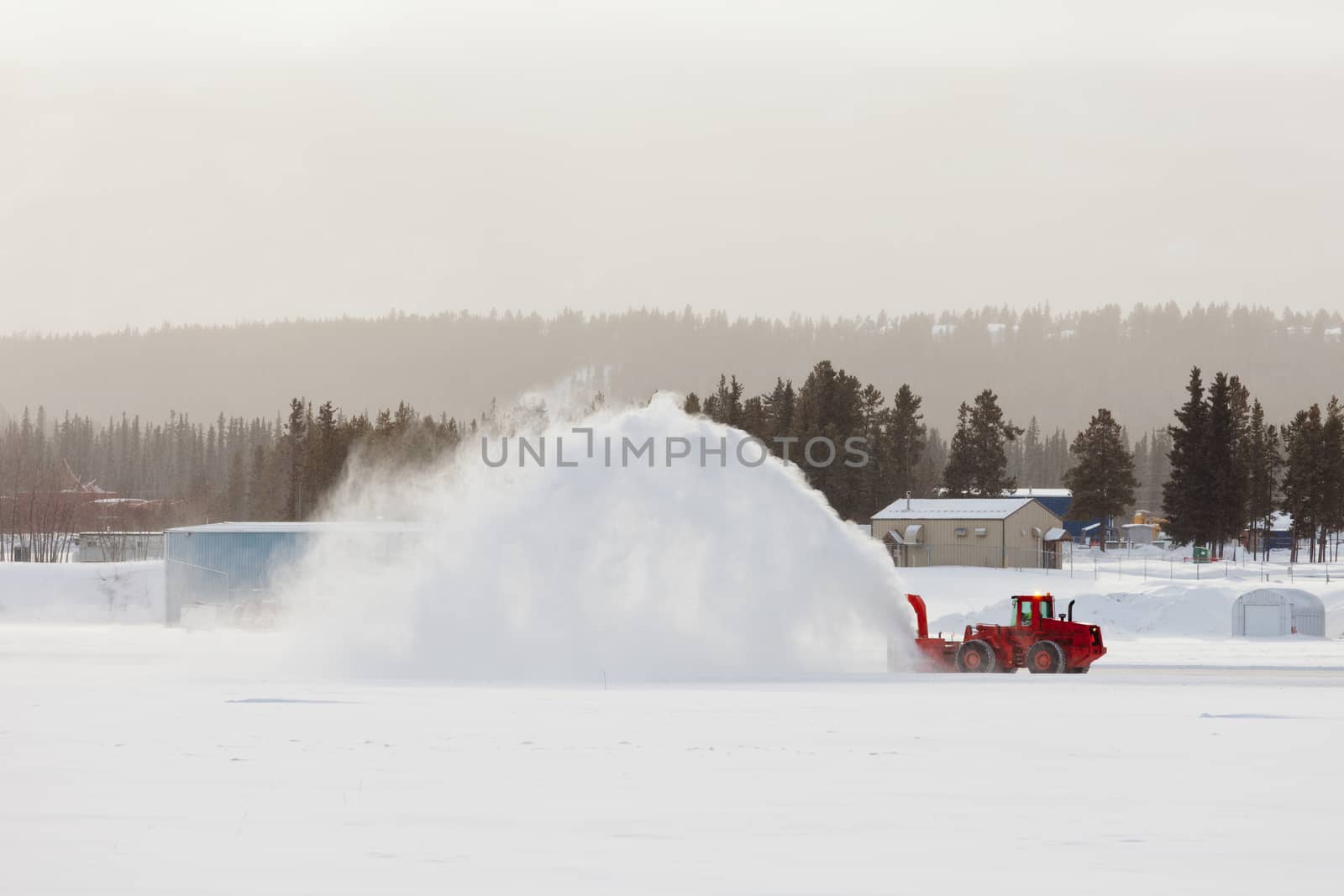 Snow thrower truck clearing road after whiteout winter snowstorm blizzard for vehicle access