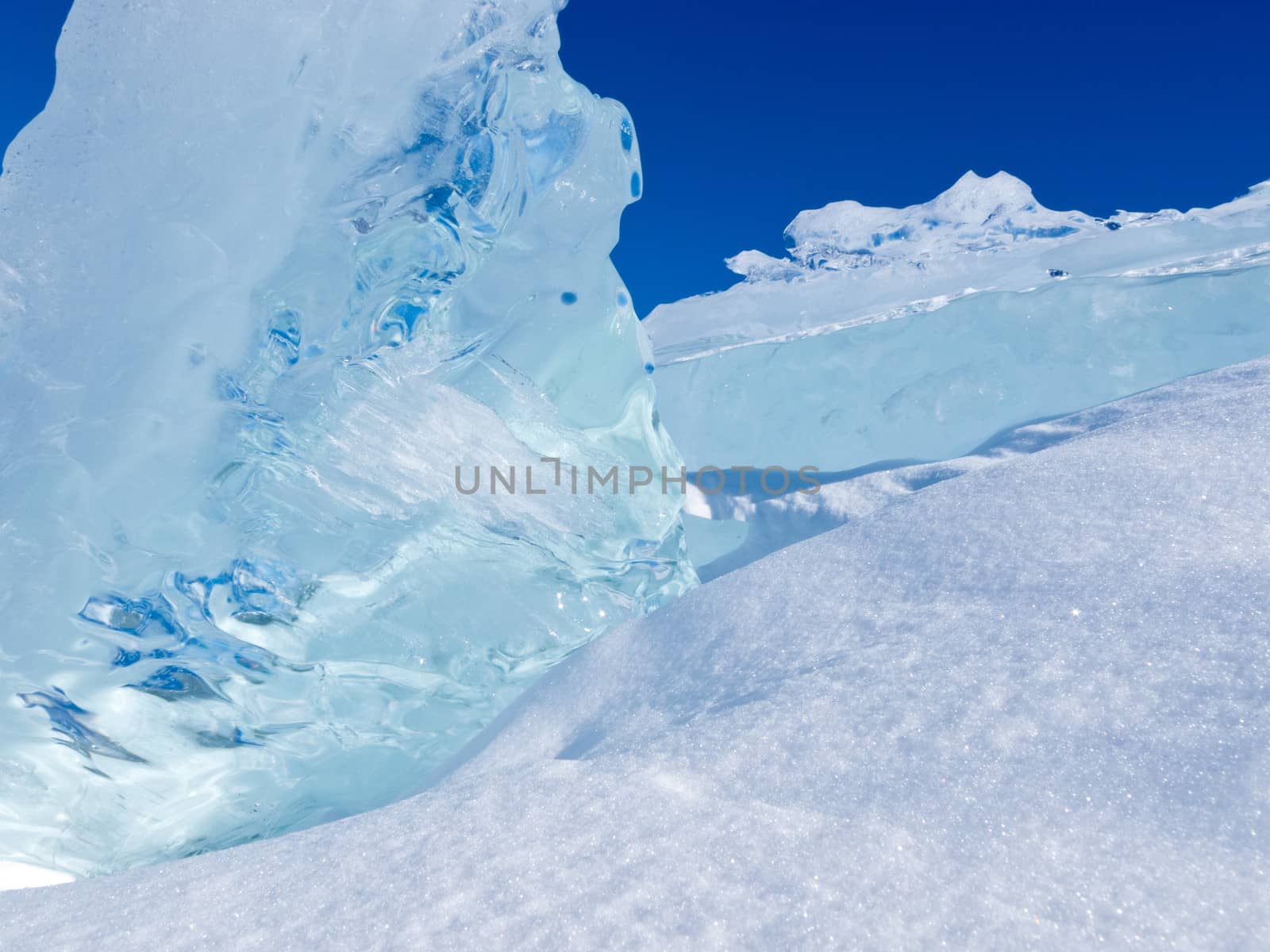 Clean clear ice chunks of glacier piled up with some fresh snow and blue sunny sky