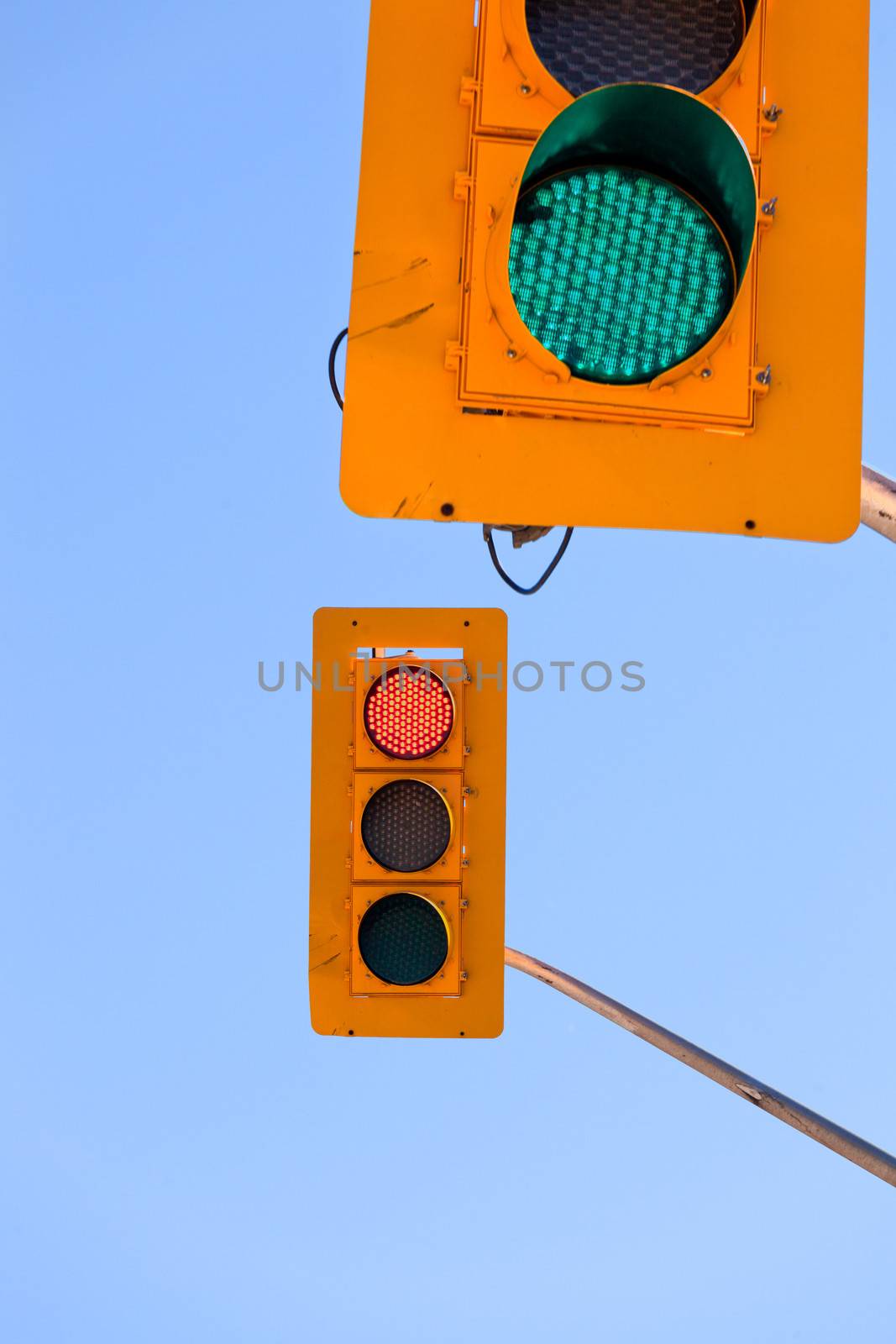 Two traffic lights, green and red, confusing and contradicting against blue sky with copyspace