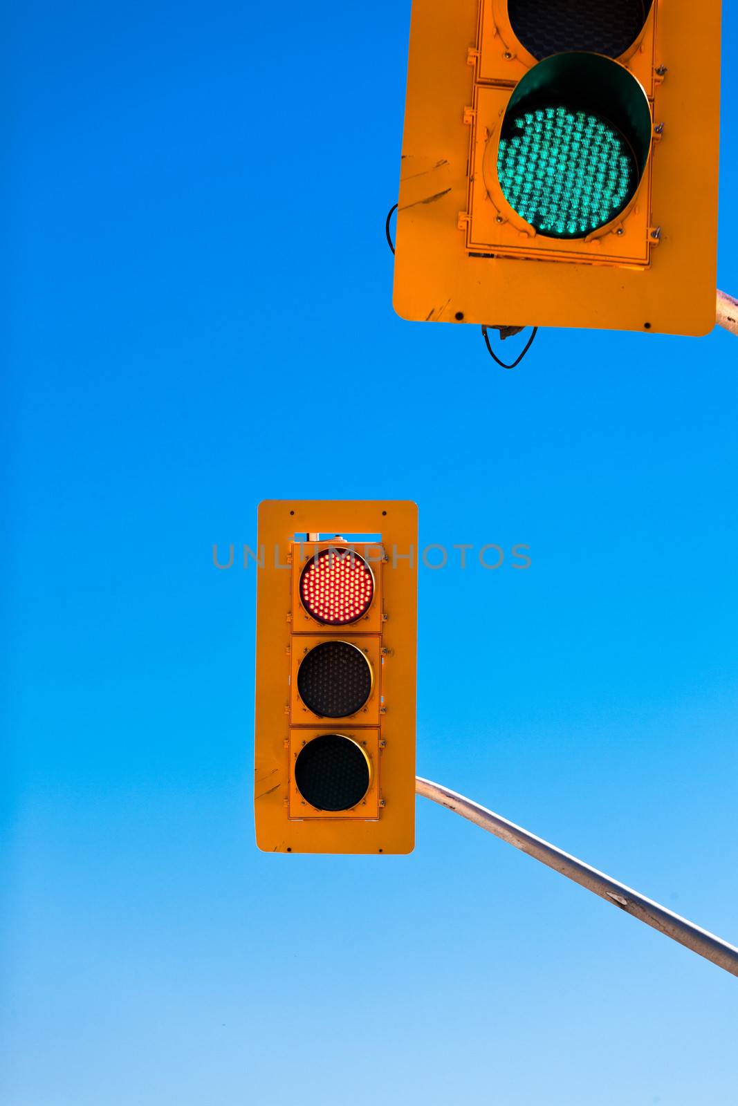 Two traffic lights, green and red, confusing and contradicting against blue sky with copyspace