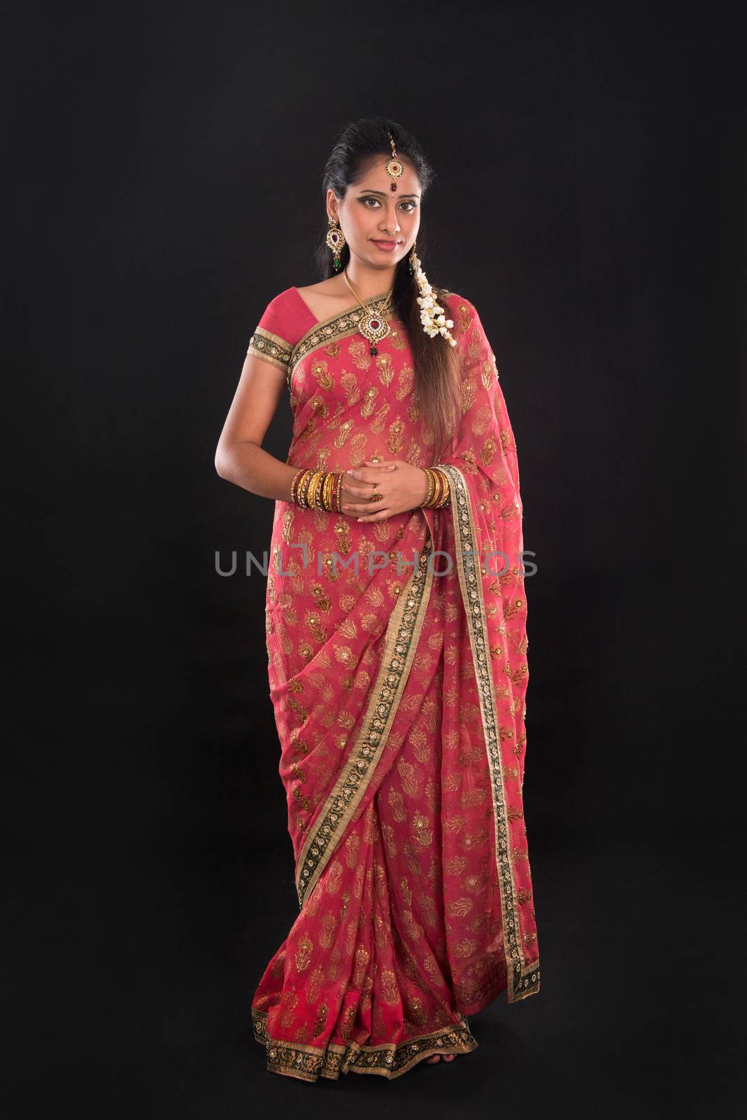 Full body traditional Indian girl in sari costume standing isolated on black background.
