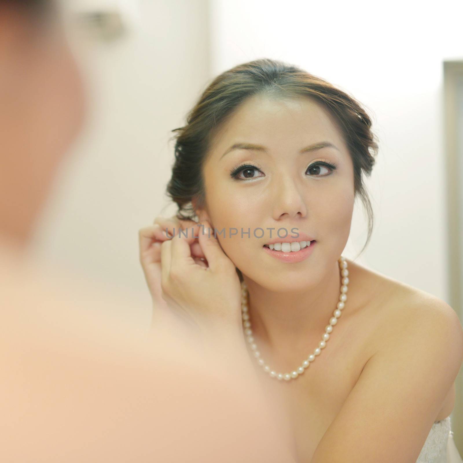 Asian bride wearing earrings on her wedding day. 