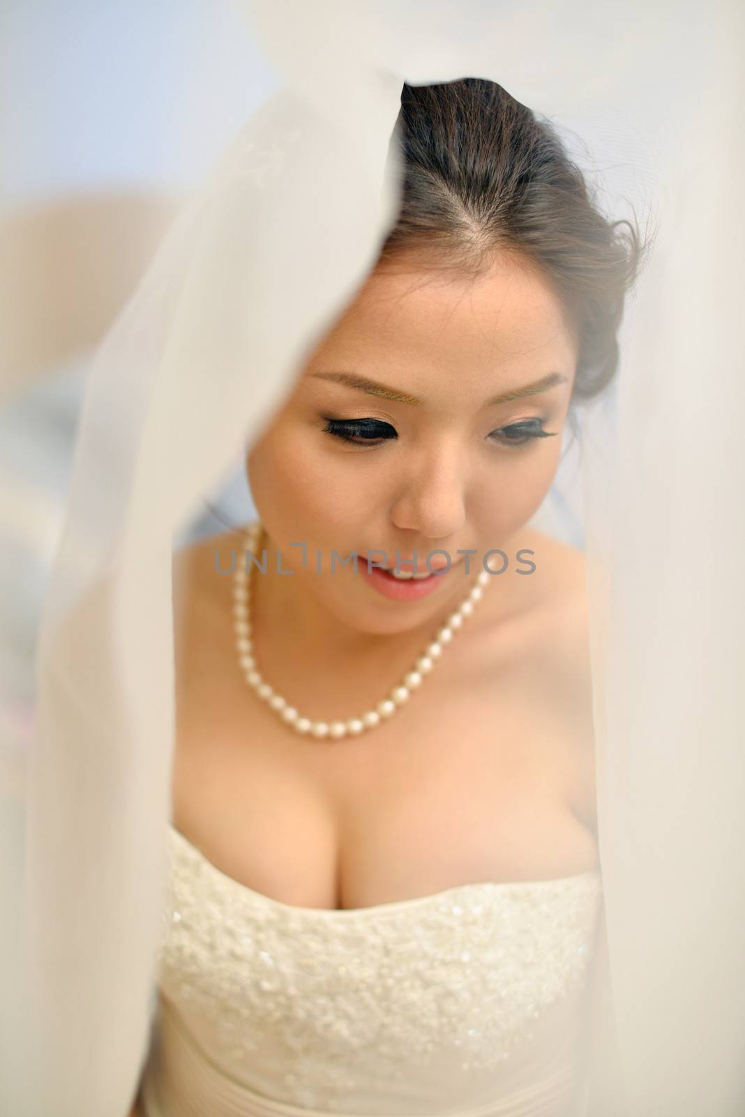 Beautiful Asian bride smiling under the veil on wedding day.