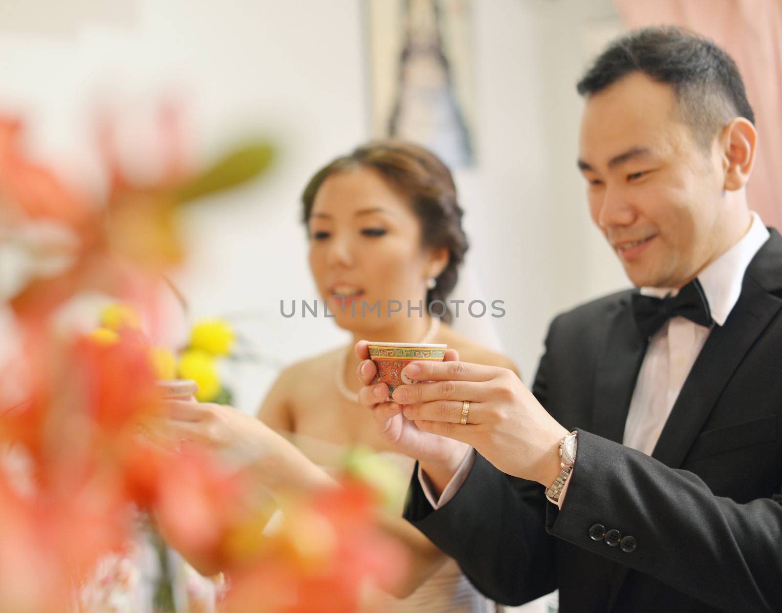 Traditional Chinese wedding tea ceremony, bride and groom, focus on hand and teacup.