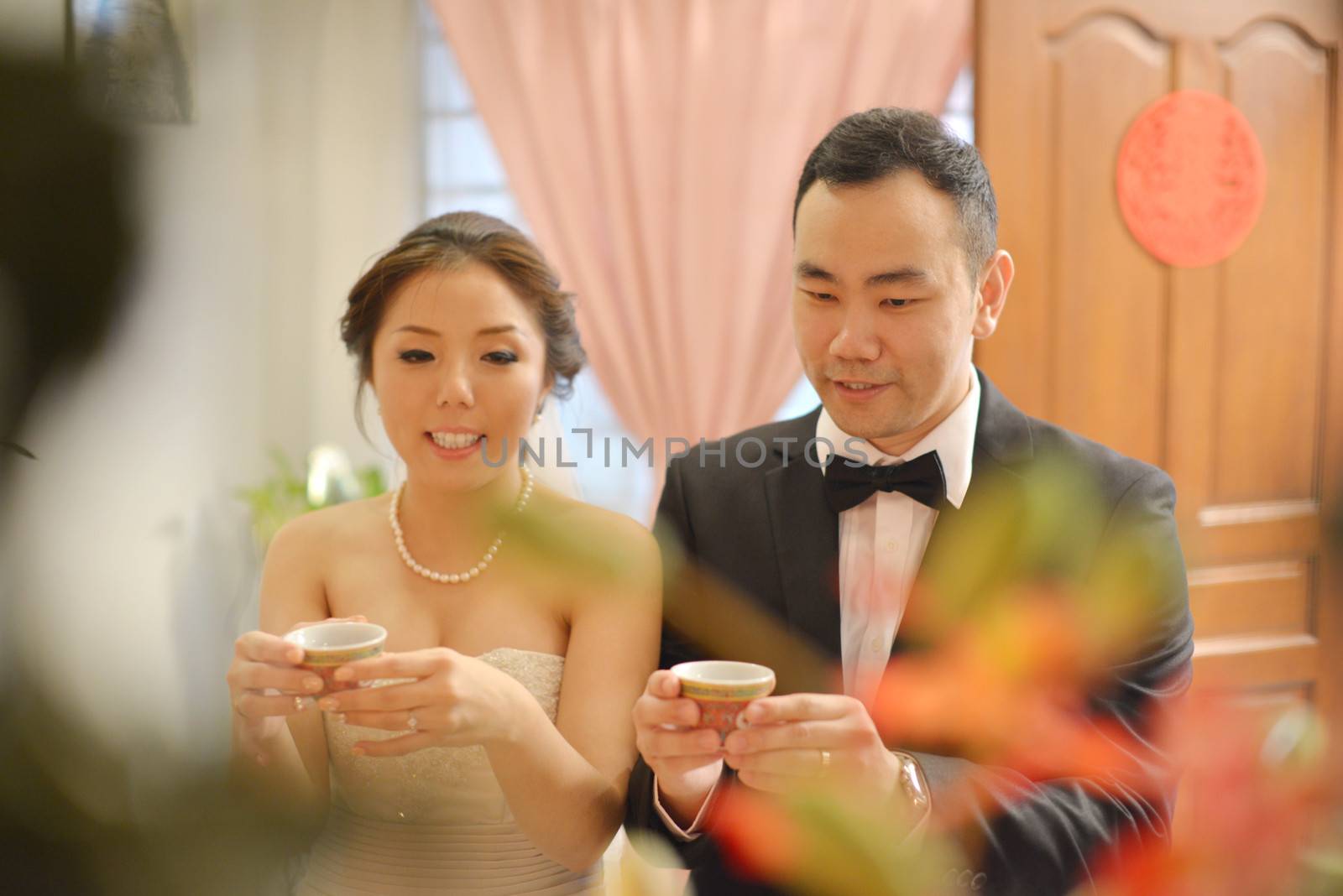 Traditional Chinese wedding, bride and groom serving tea in ceremony.