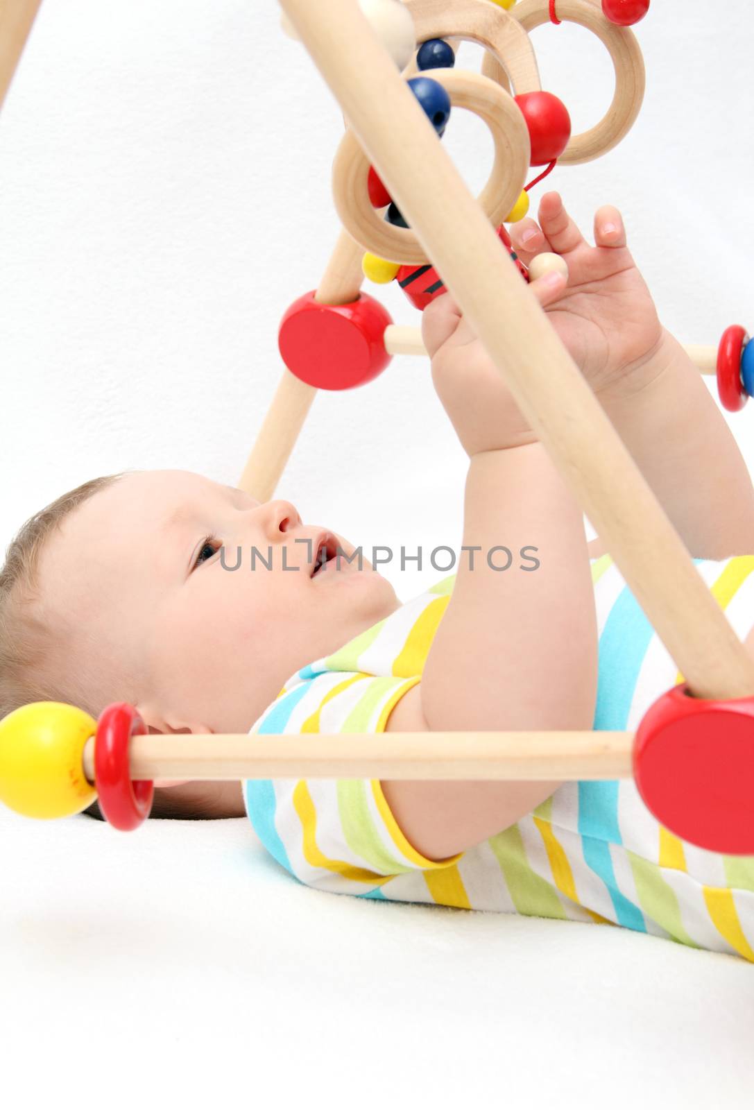 Beautiful baby on back playing with toys