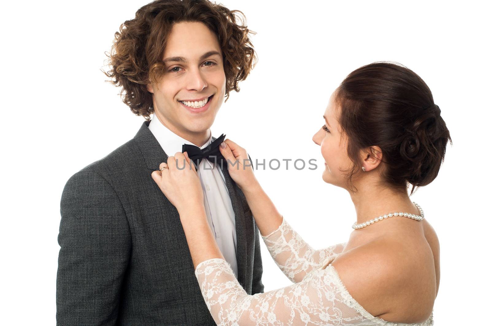 Bride adjusting her man's bow tie by stockyimages