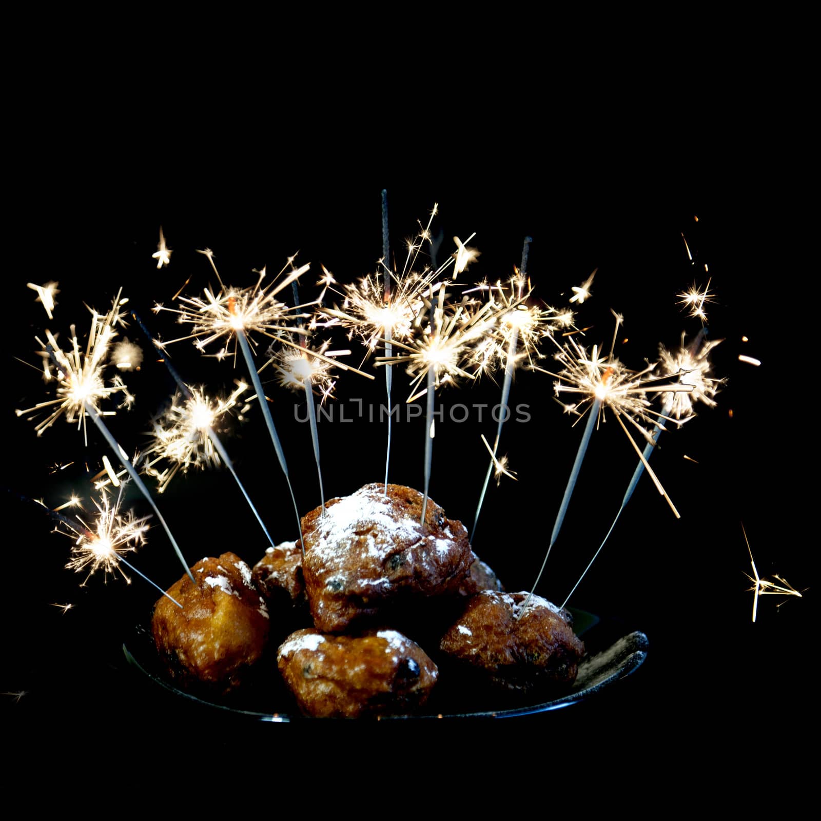 a pile with oliebollen with fireworks on a plate on a white background