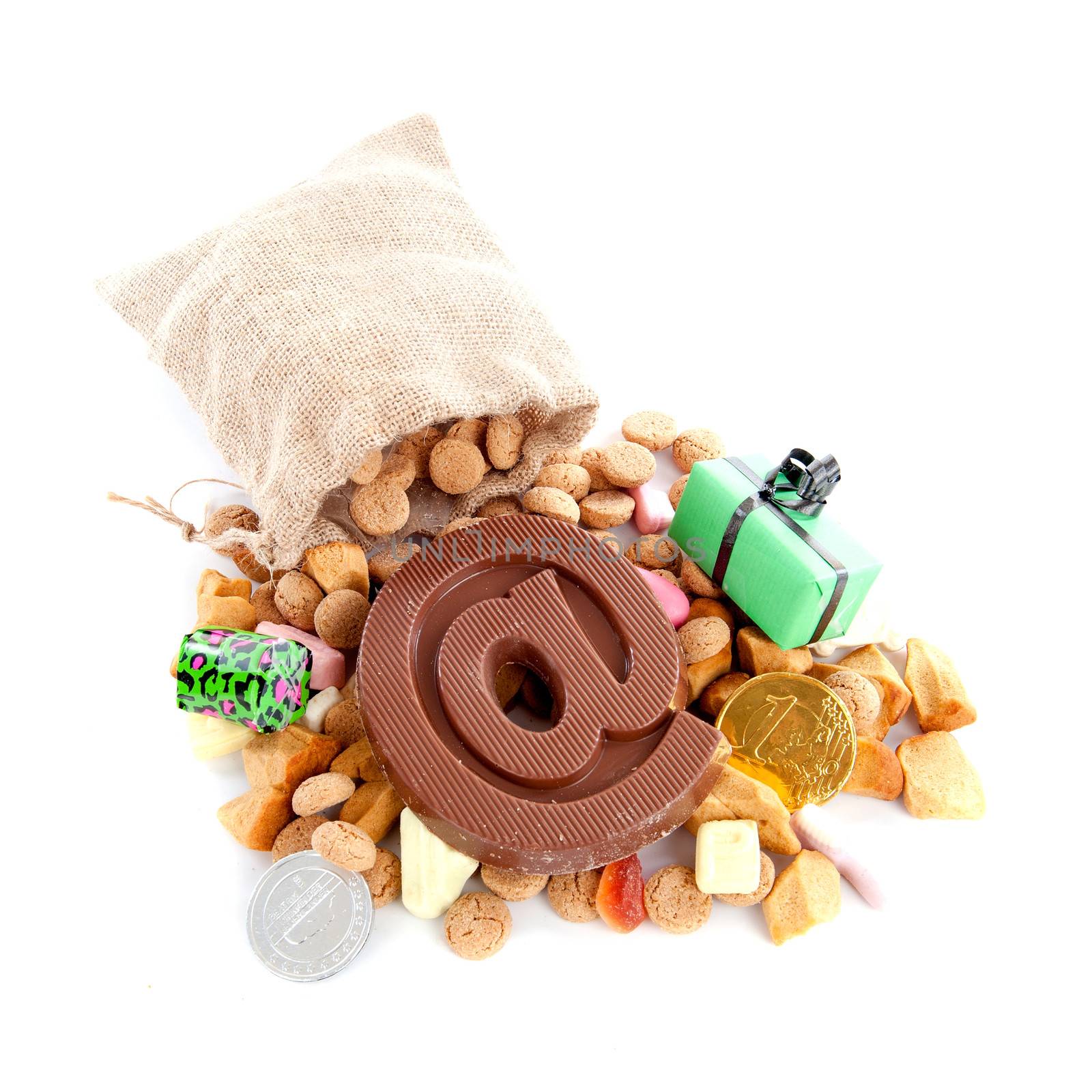a jute bag with pepernoten, candies and a atpersand, made of chocolate on a white background