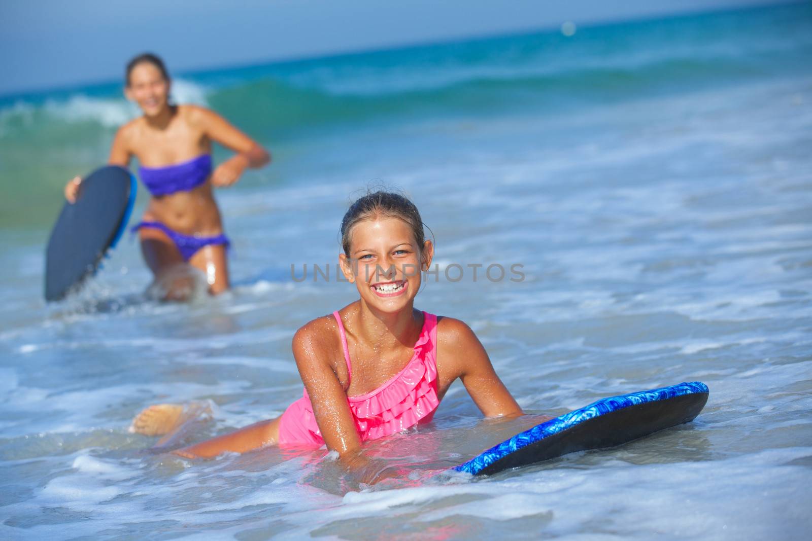 Summer vacation - Two cute girls having fun with surfboard in the ocean