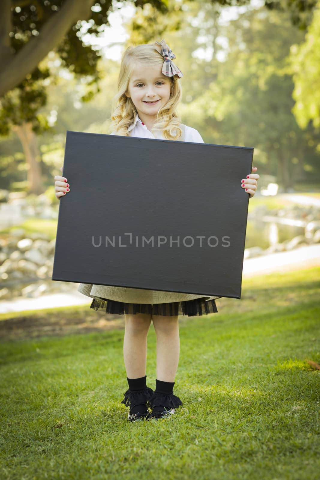 Cute Little Blonde Girl Holding a Black Chalkboard Outdoors
 by Feverpitched