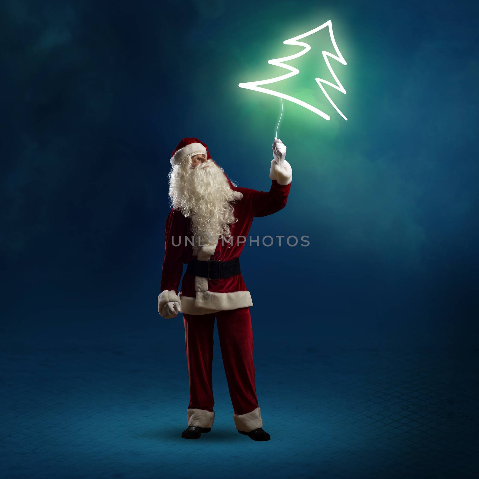 Santa Claus is holding a shining Christmas tree sign on a string