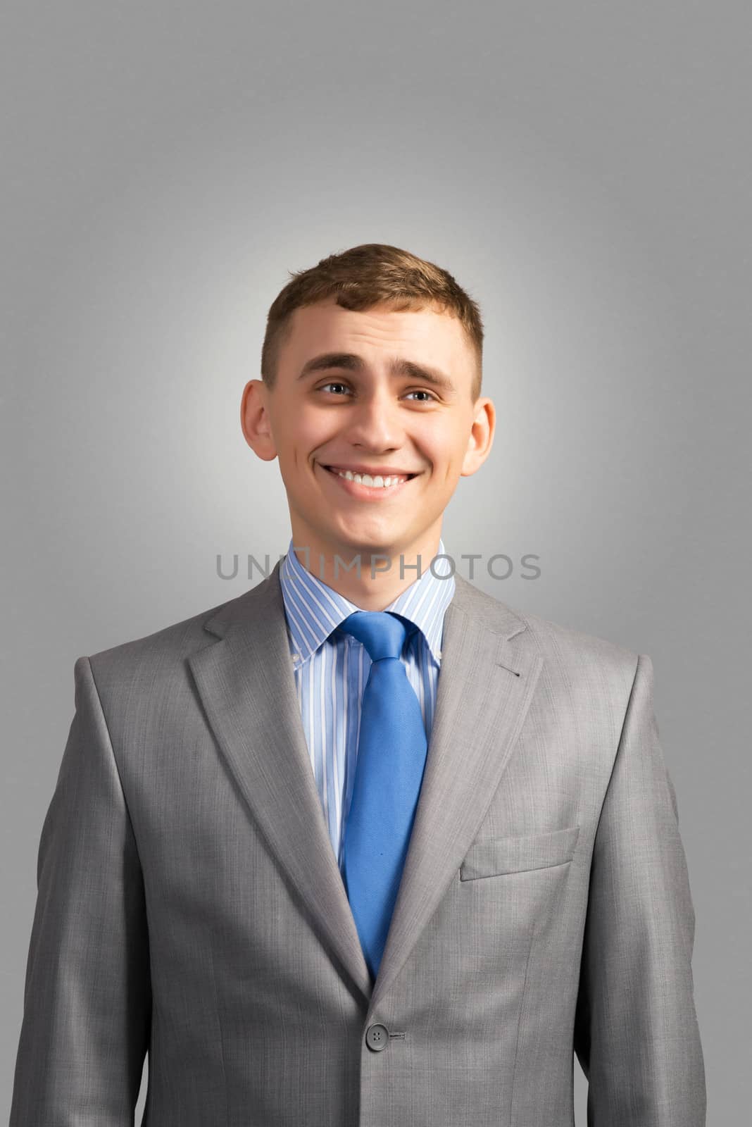 Portrait of a young businessman smiling, on a gray background